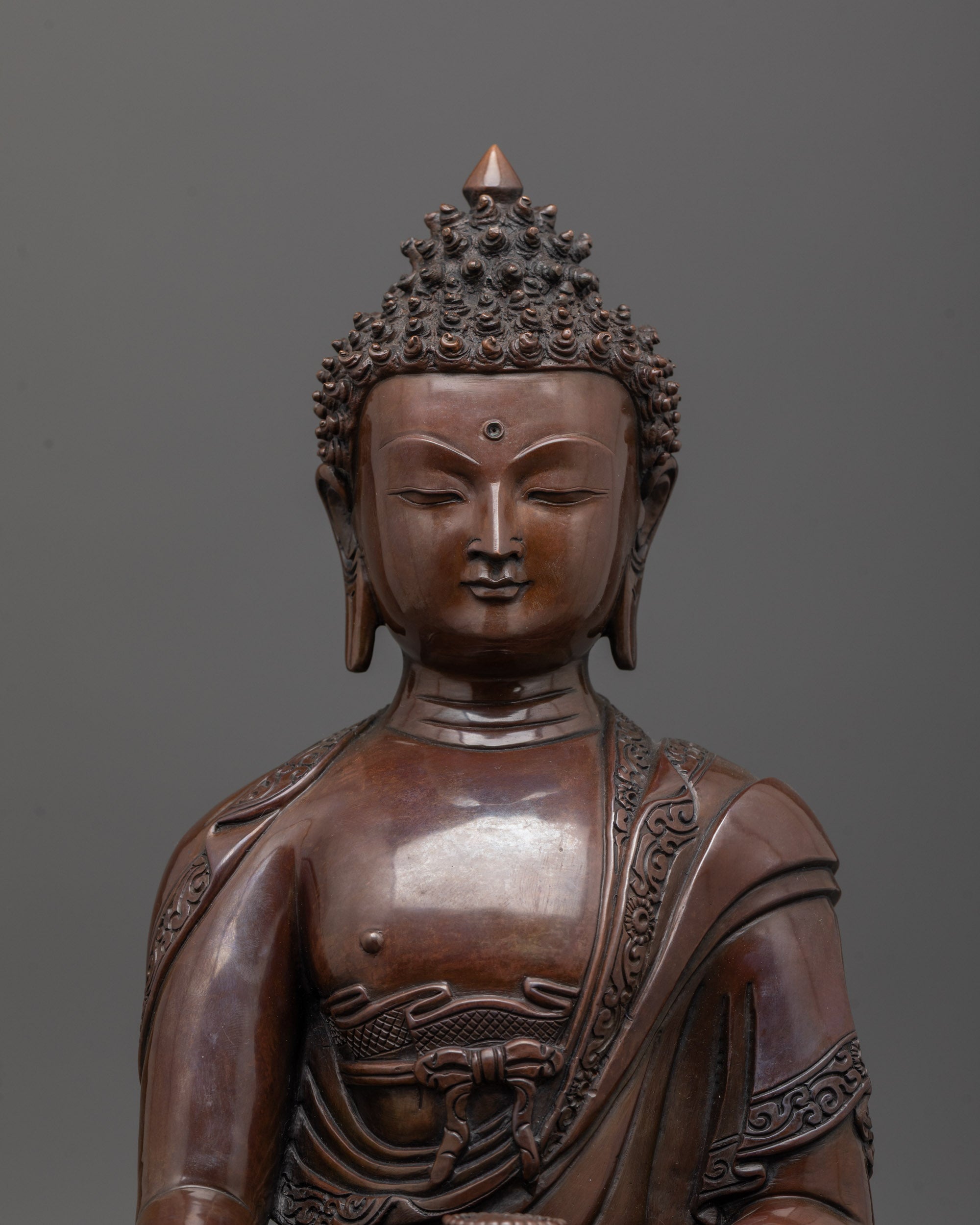 Close up of Shakyamuni Buddha statue face with oxidized copper and monk’s robe details