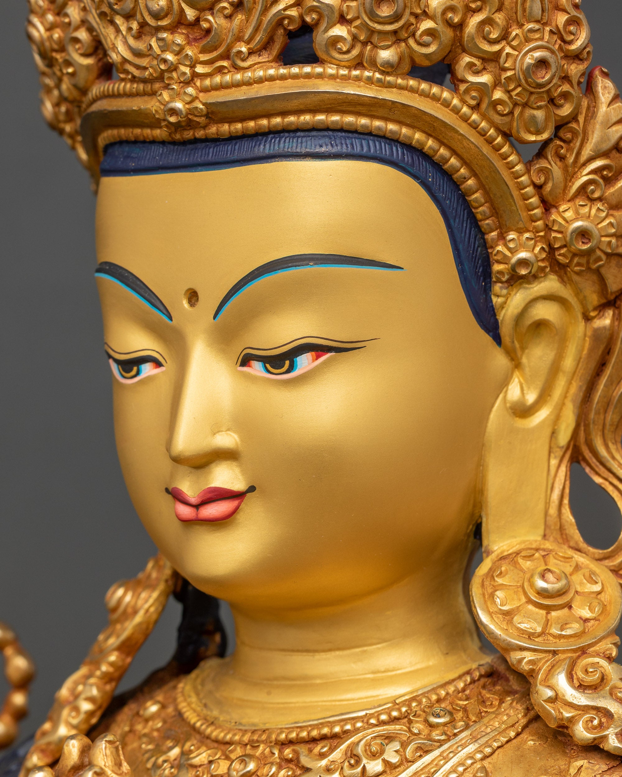 Chenrezig face side close-up, gold fire-gilded copper with serene expression