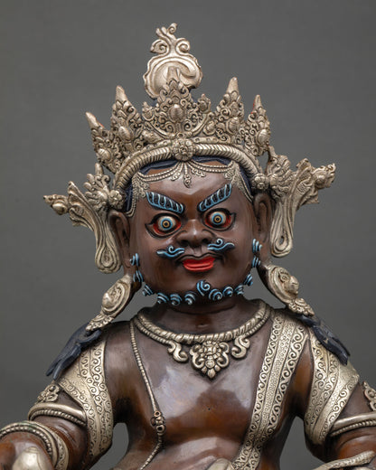 Close up of Dzambhala statue showing wealth deity attributes silver-plated details and lotus seat