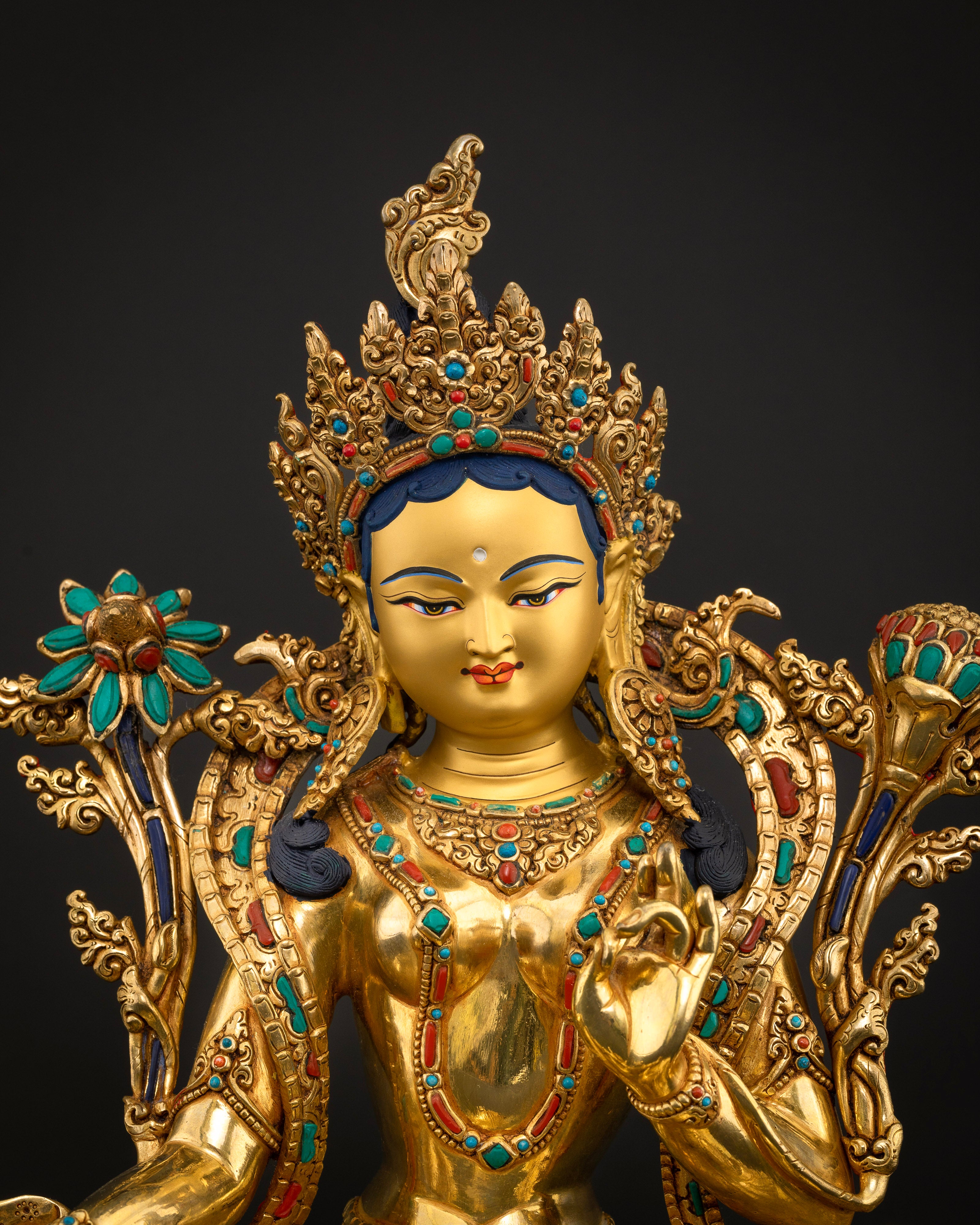 Close up Green Tara sculpture gold-painted face ornate crown lotus stems Buddhist deity