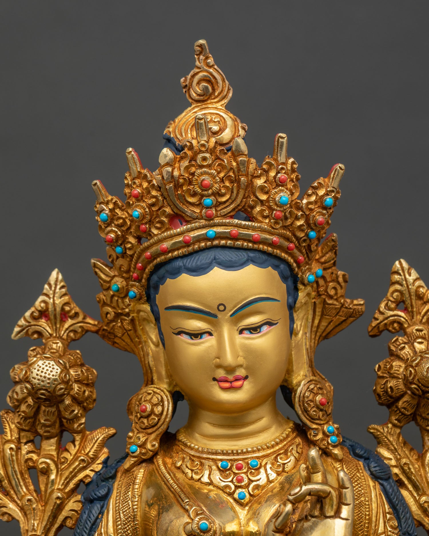 Close up Green Tara statue gold-painted face semi-precious stones hand-carved details