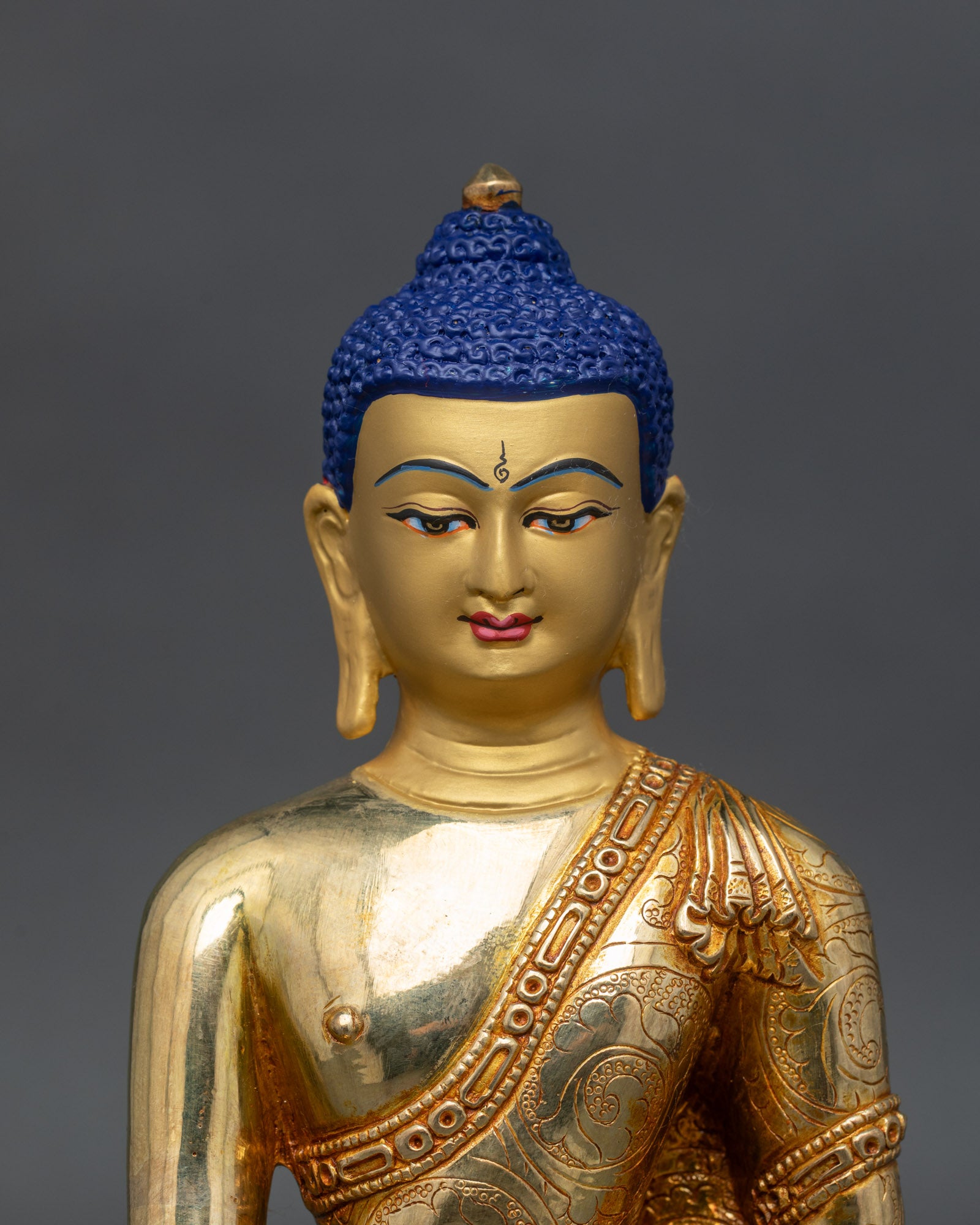 Close up view of Shakyamuni Buddha statue, serene gold painted face with floral motif details