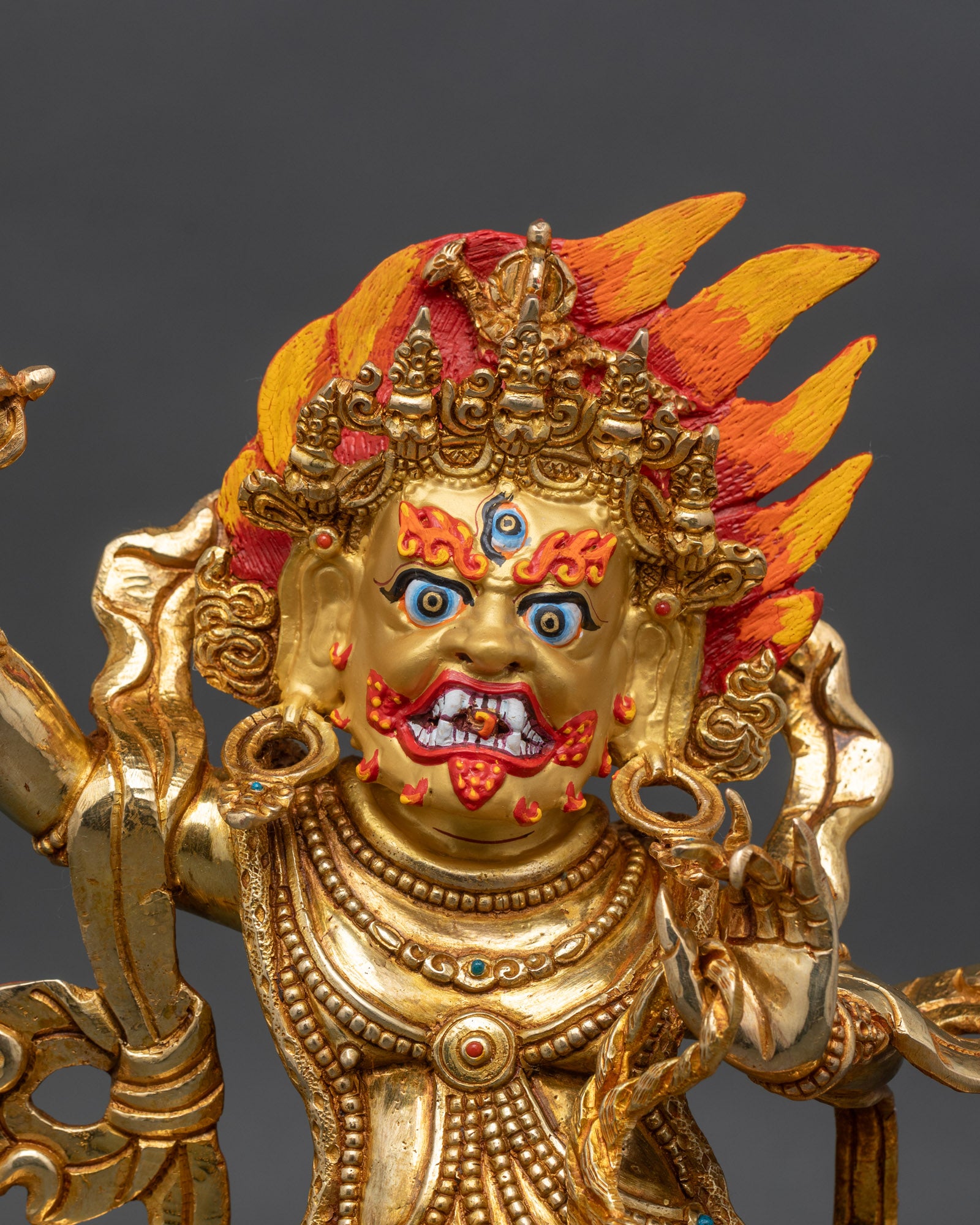 Close up Vajrapani face fierce expression gold painted details vajra Buddhist sculpture
