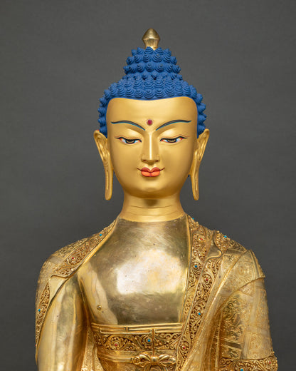 Close-up front view of gold gilded Shakyamuni Buddha statue face and carved robe