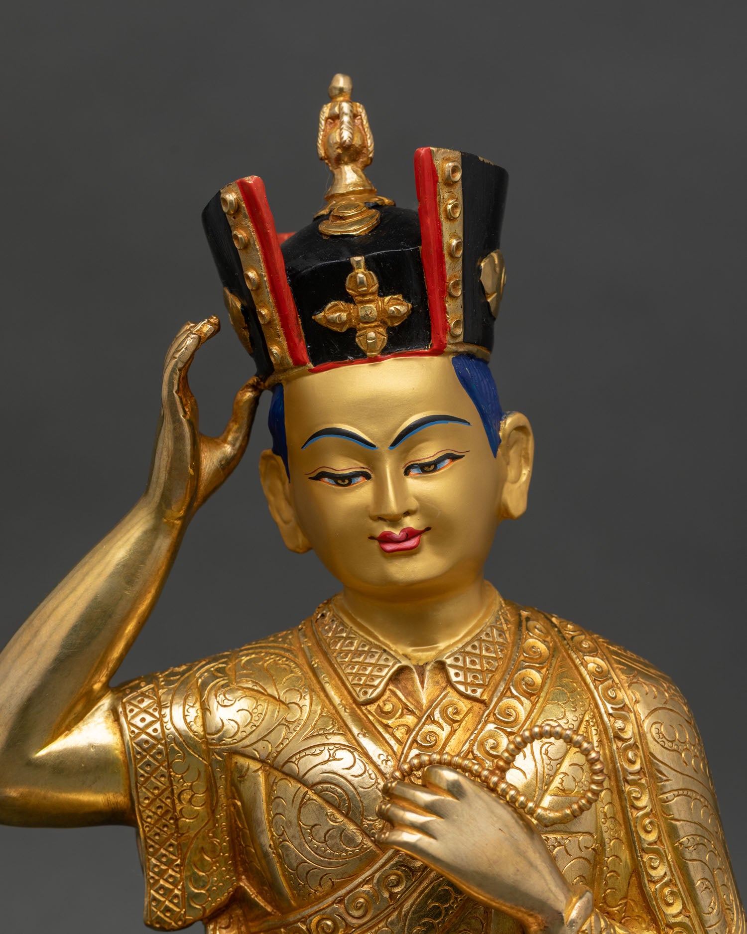 Close up of 16th Karmapa Statue serene face black hat crystal rosary intricate monk robes Buddhist sculpture