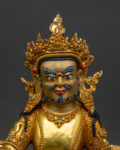 Close up of Dzambhala Statue gold-painted face holding citrons precious jewels sacred Buddhist deity