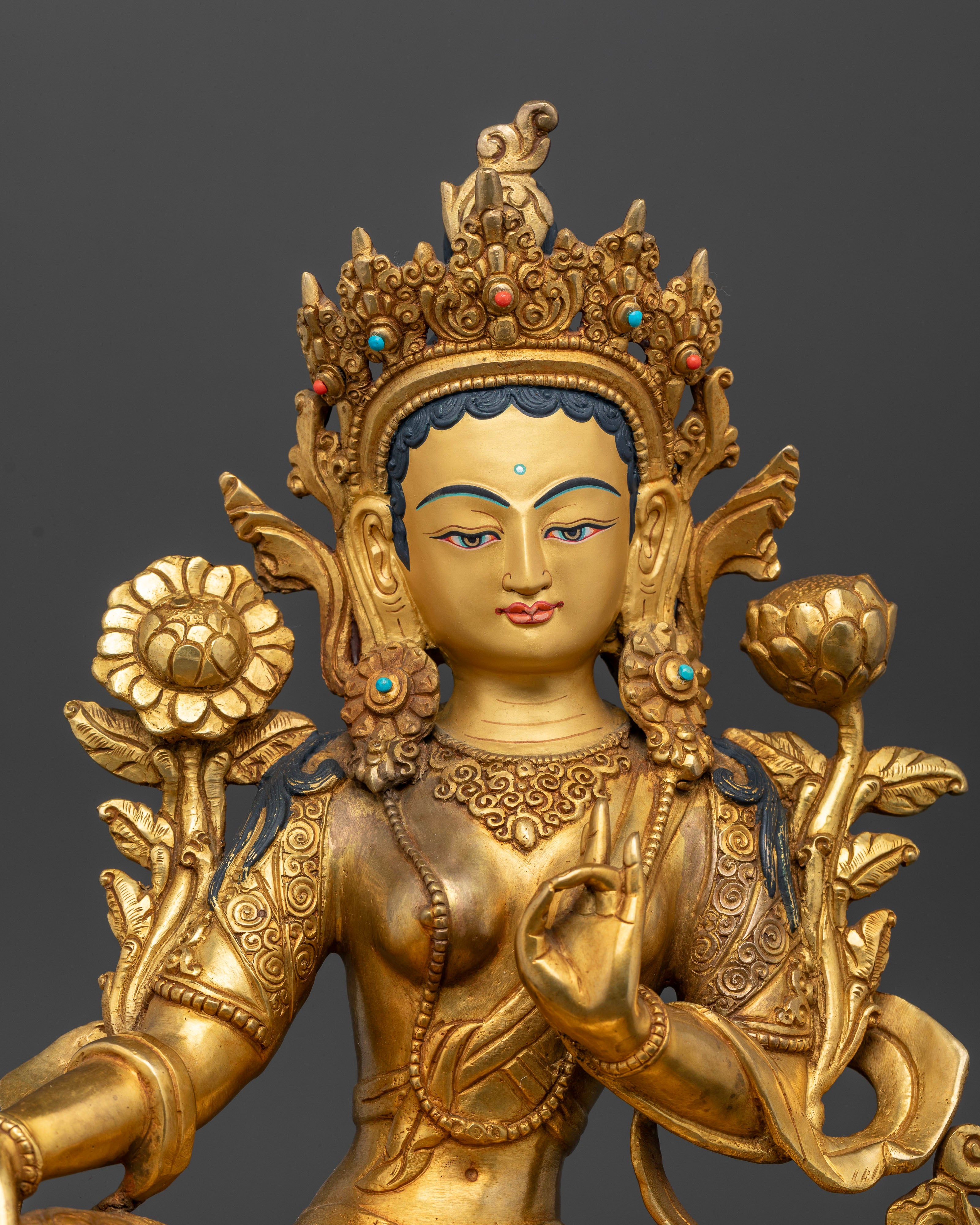 Close up of Green Tara Statue serene face intricate carved robes holding lotus flower Varada Vitarka mudras