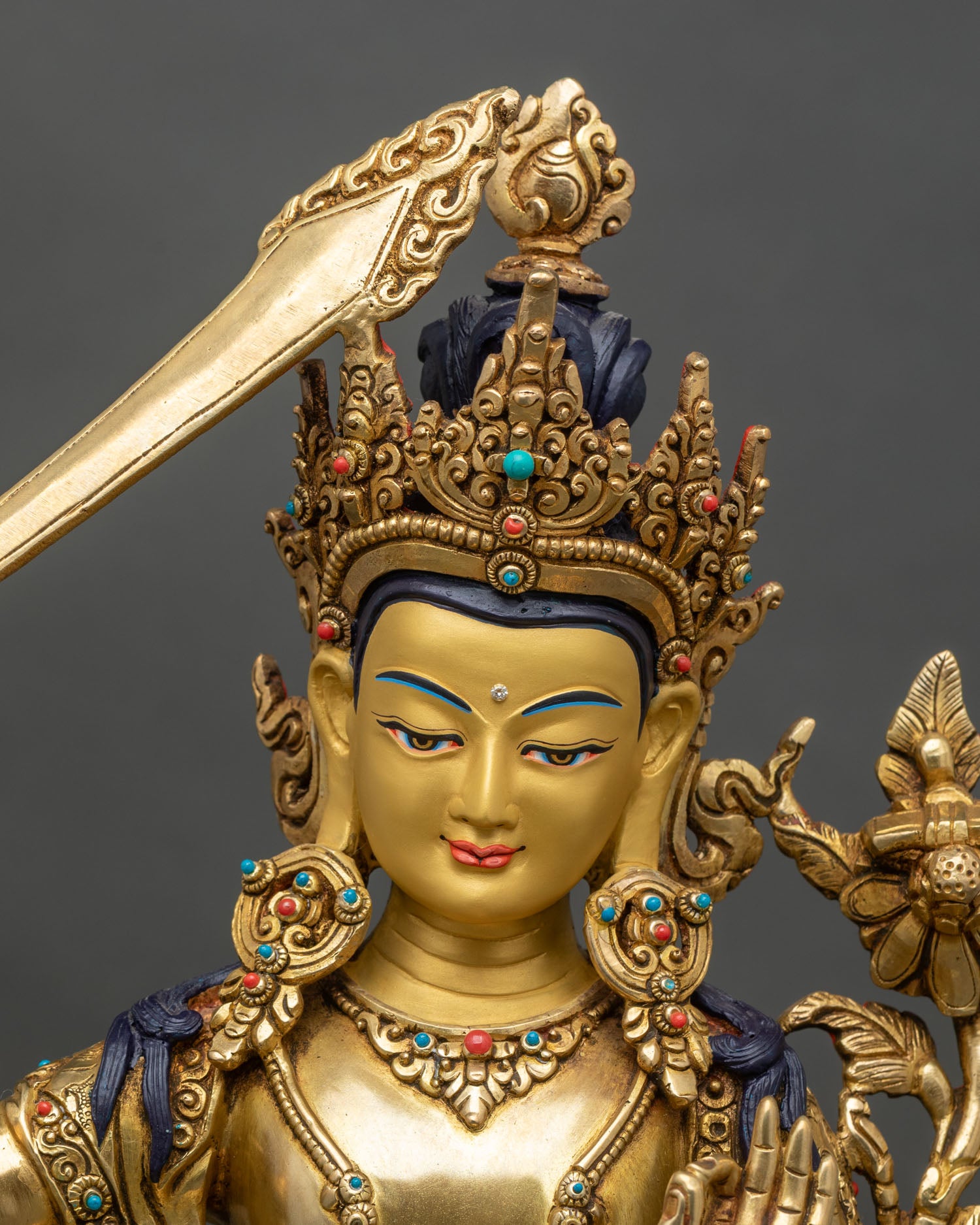 Close-up of Manjushri statue showing gold gilding, lotus seat, and engraved robes