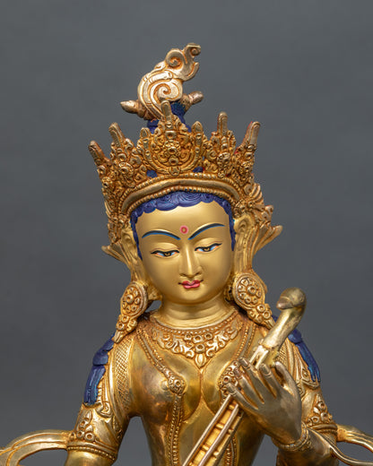 Close up of Saraswati statue showing intricate copper carving and gold gilded details