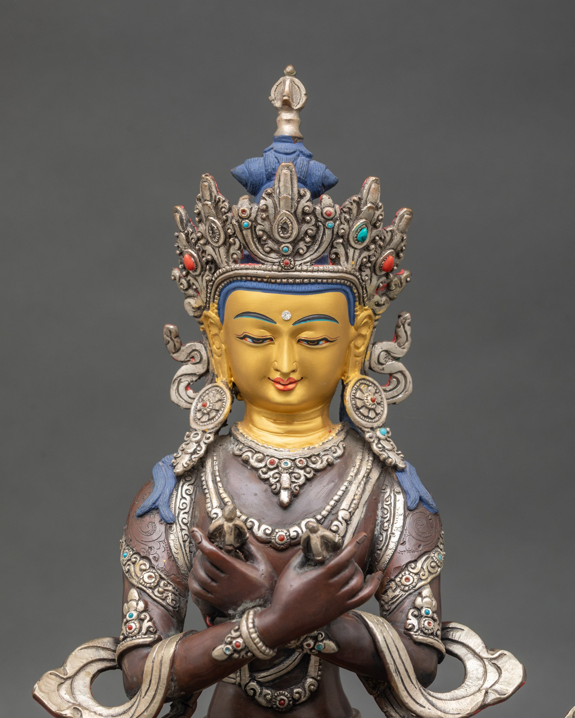 Close-up of Vajradhara Buddha statue showing vajra and bell details, silver-plated copper finish