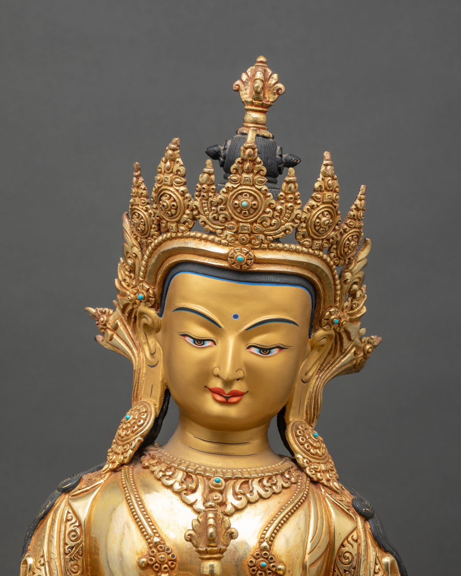 Close up of Vajrasattva Buddhist statue showing intricate copper carving and gold gilding