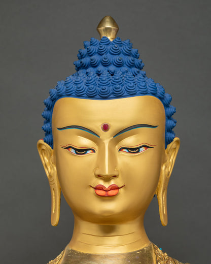 Close-up of hand-carved gold face of Shakyamuni Buddha statue with urna and blue hair