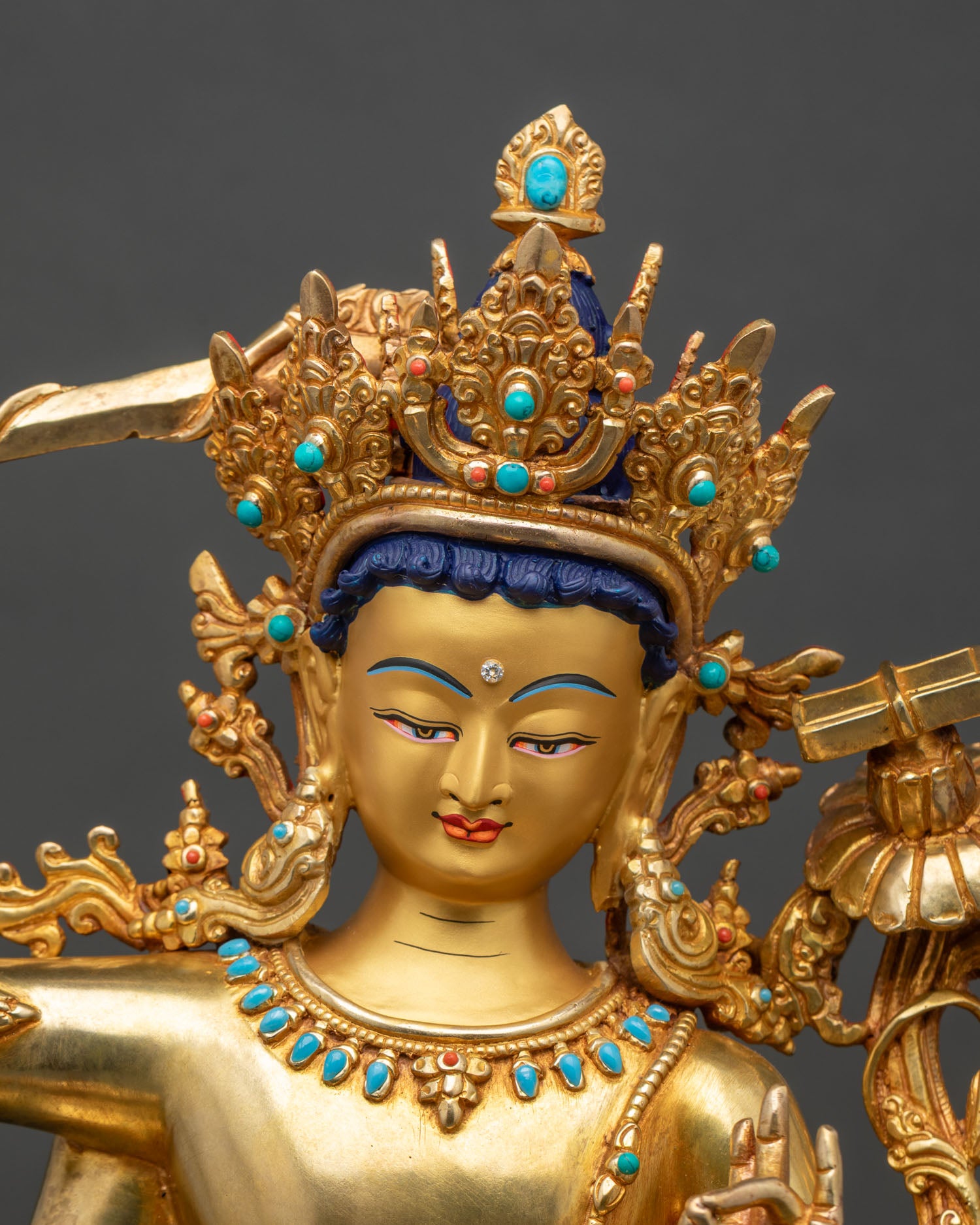 Close-up of Maha Manjushri statue showing gold gilding, lotus seat and sacred ornaments