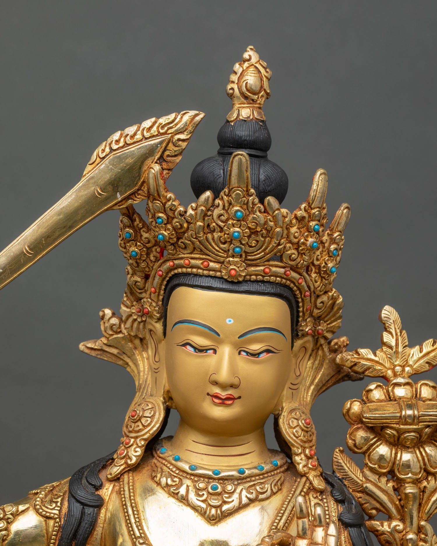 Close up of Manjushri statue showing gold gilding, lotus seat, and jeweled aureole