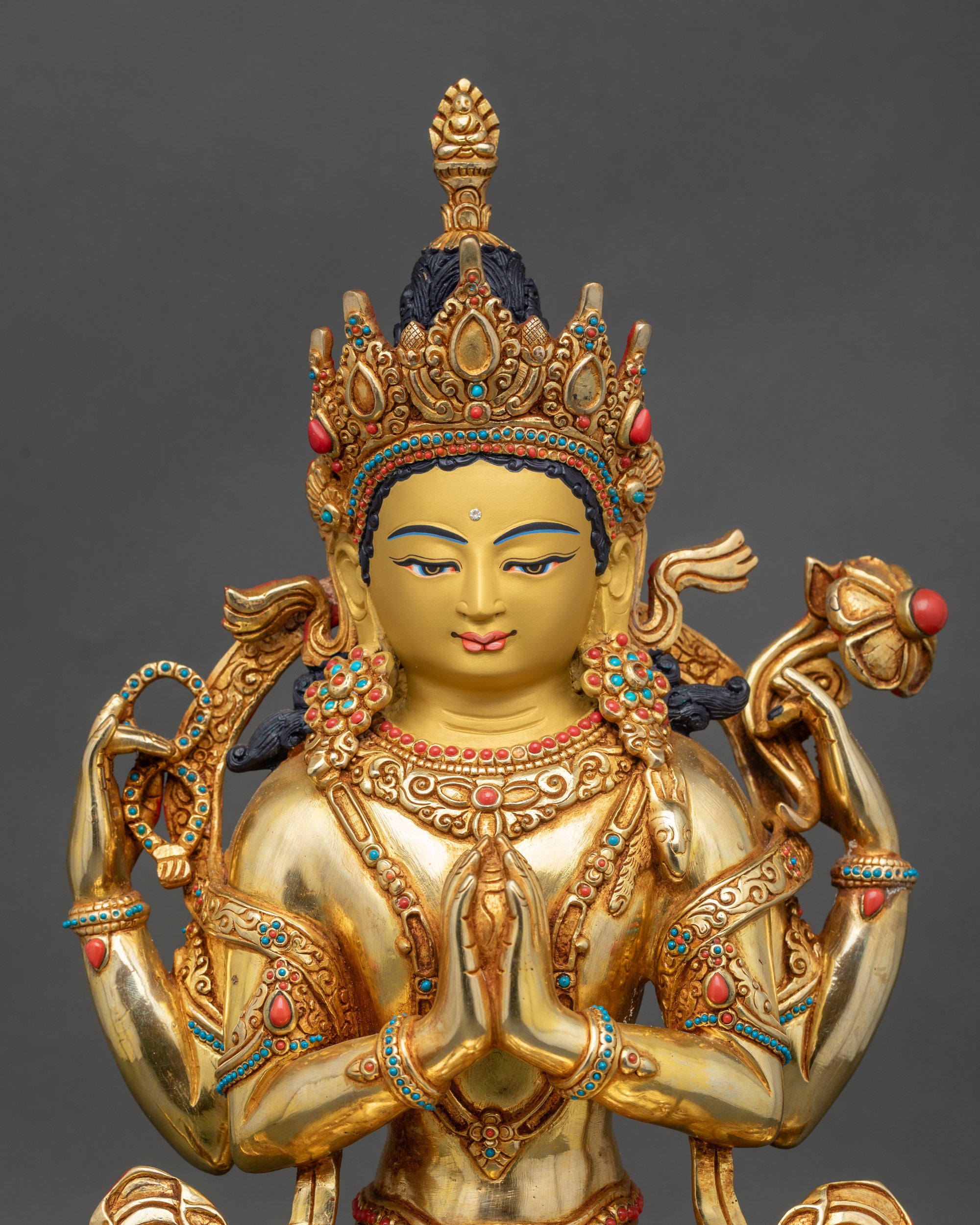 Close-up Chenrezig statue face and hands showing Anjali Mudra and lotus flower