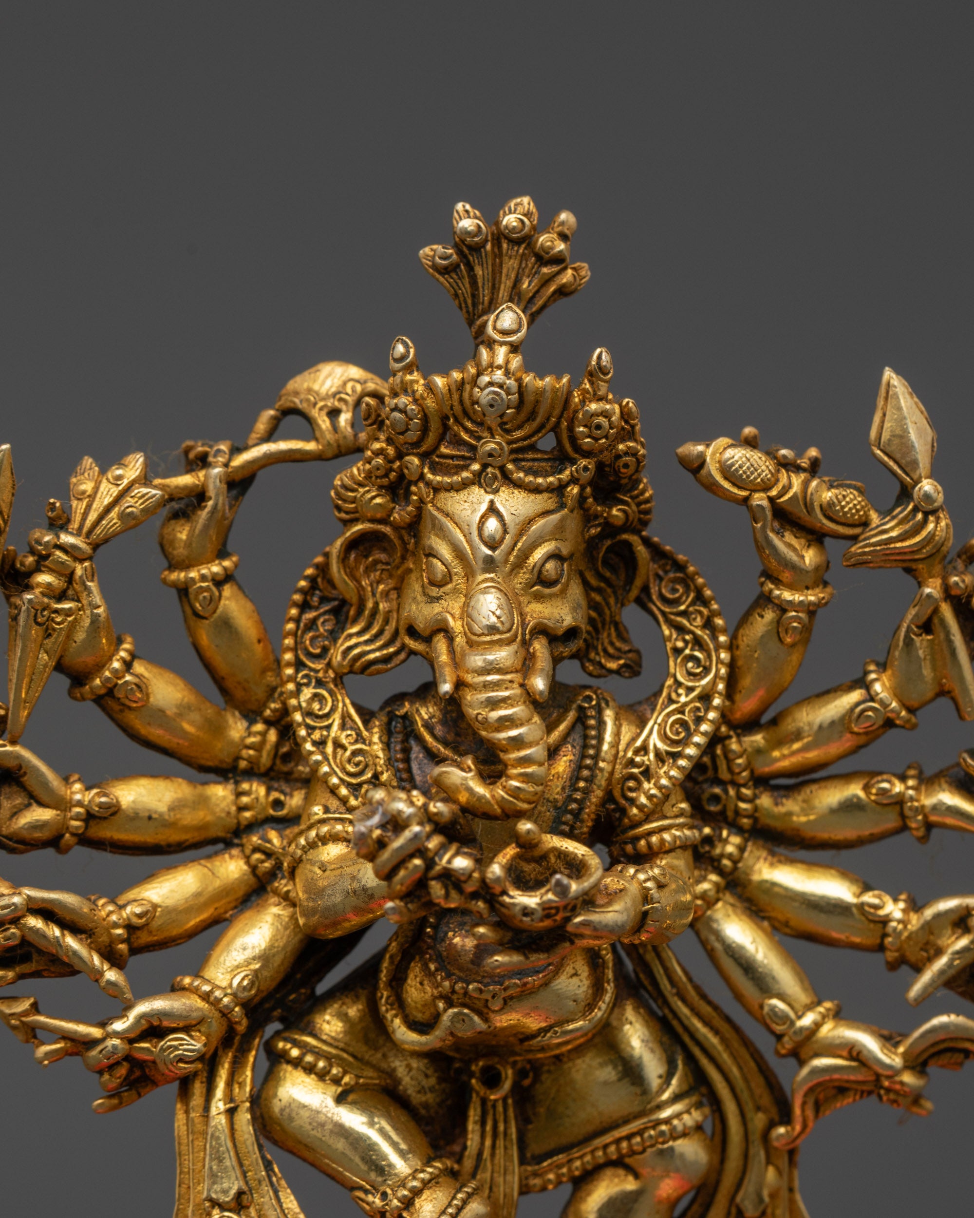 Close-up Ganesh crown, 16 arms holding sacred objects, and swirling robes