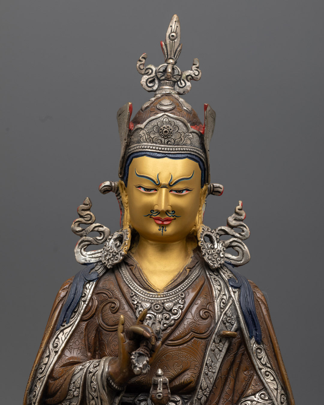 Guru Rinpoche Statue showing intricate details in oxidized copper craftsmanship and facial expressions.