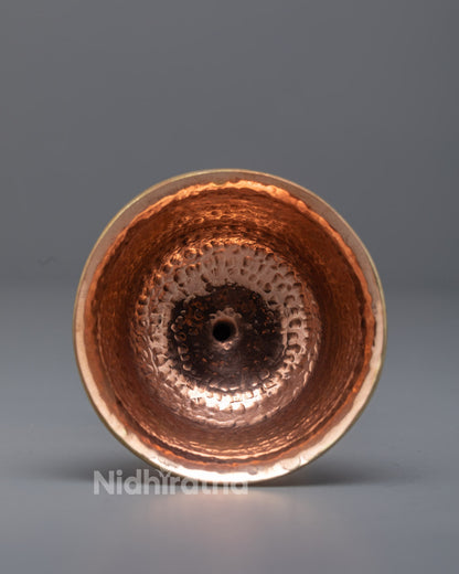 Close-up angled shot of traditional copper butter lamp glowing with flickering flame