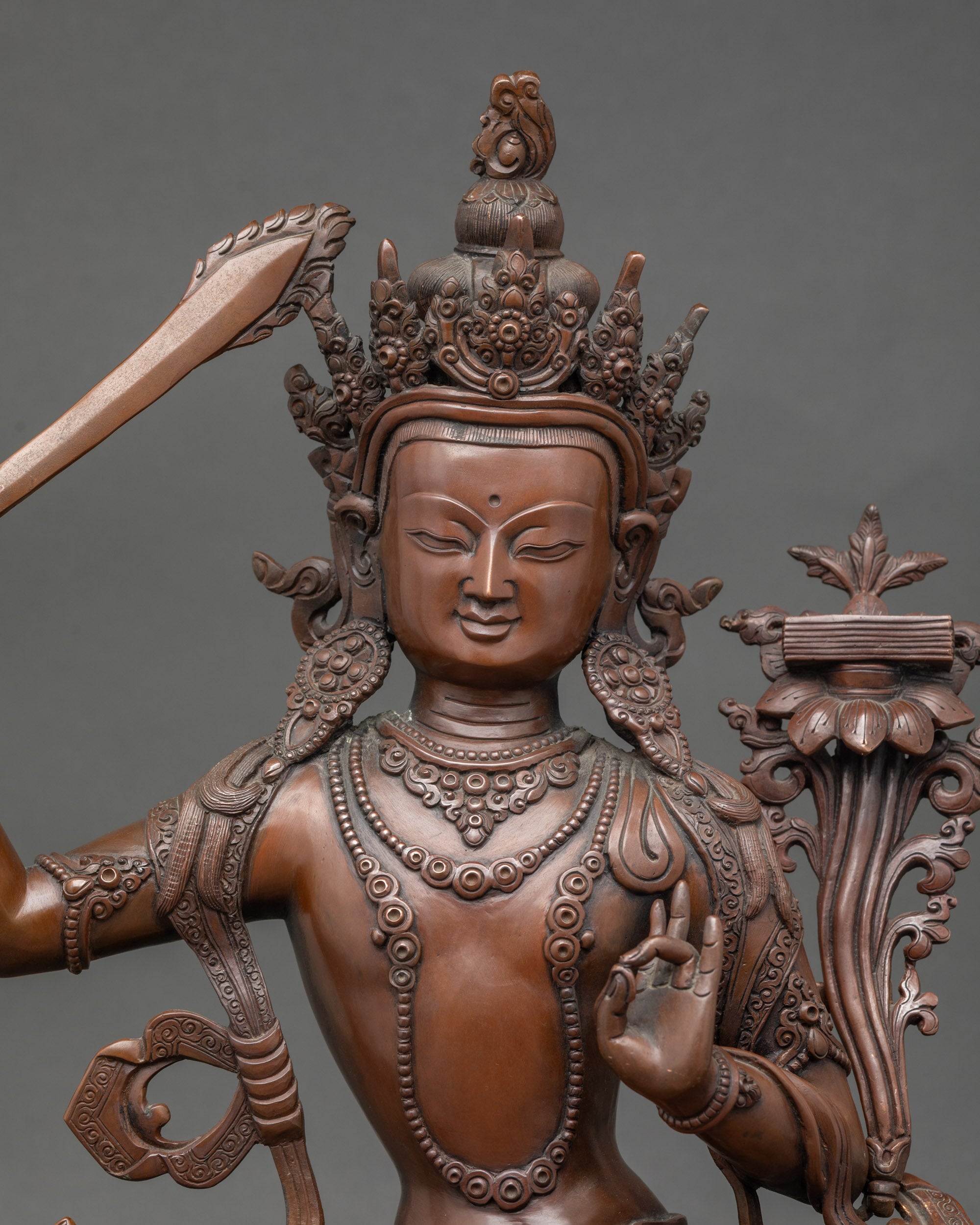 Close-up face – Detailed oxidized copper Manjushri statue face with serene expression, depicting Buddhist wisdom and spiritual insight.