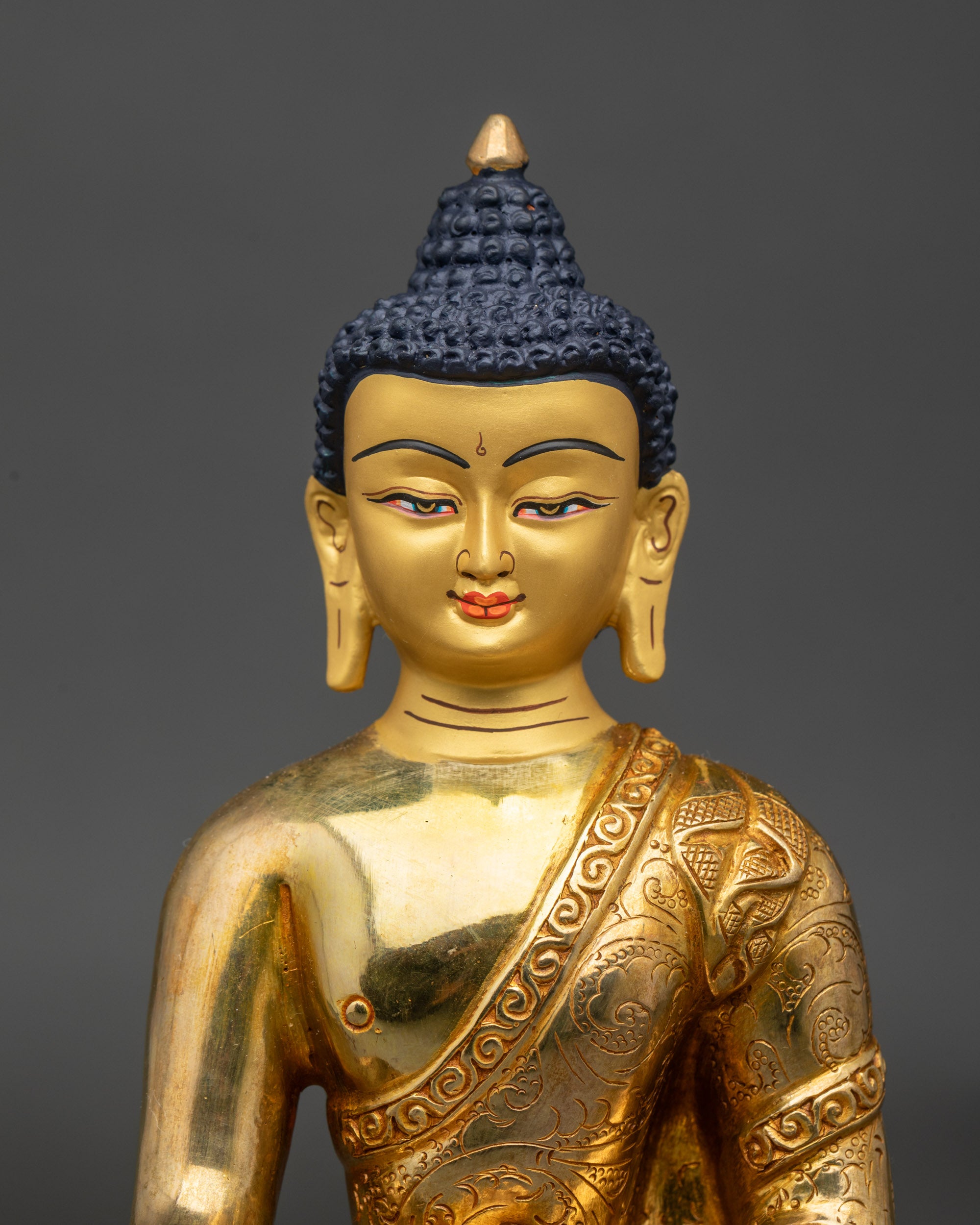 Close-up gold-painted face Buddha Shakyamuni statue intricate floral motifs