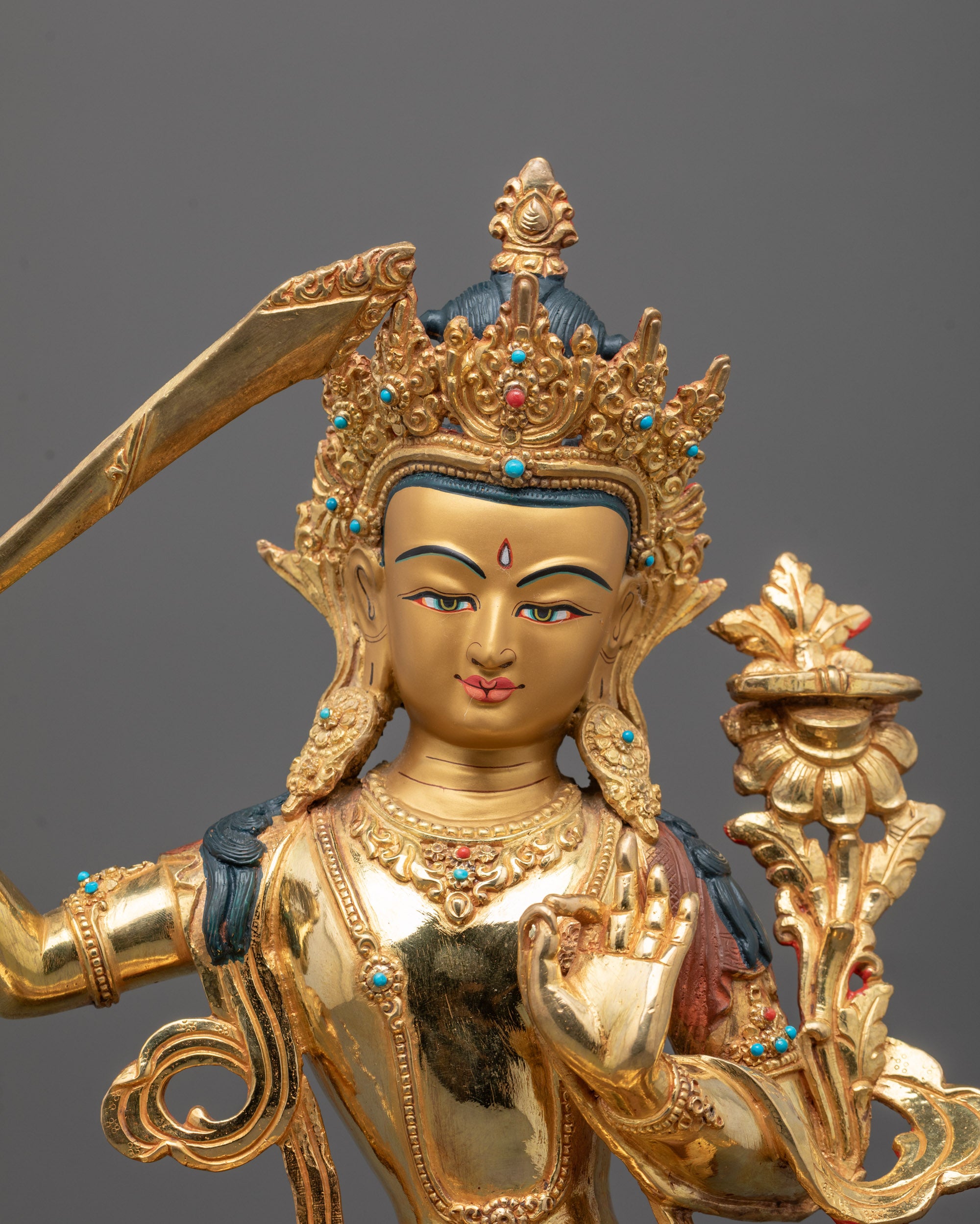 Close-up of 24k fire gold gilded face of Manjushri showing serene expression
