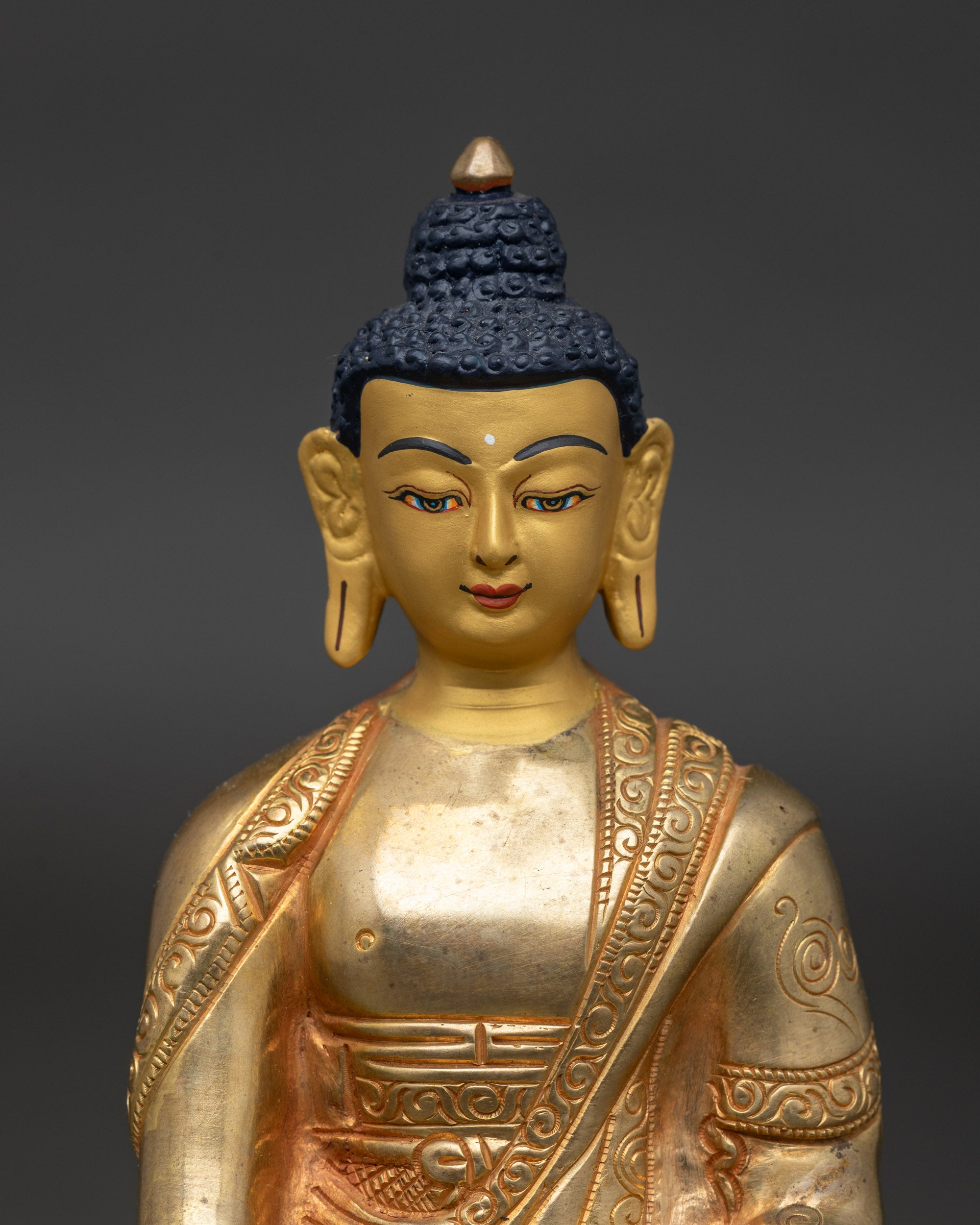 Close-up of Amitabha Buddha face, 24K gold-painted and fire-gilded Himalayan sculpture