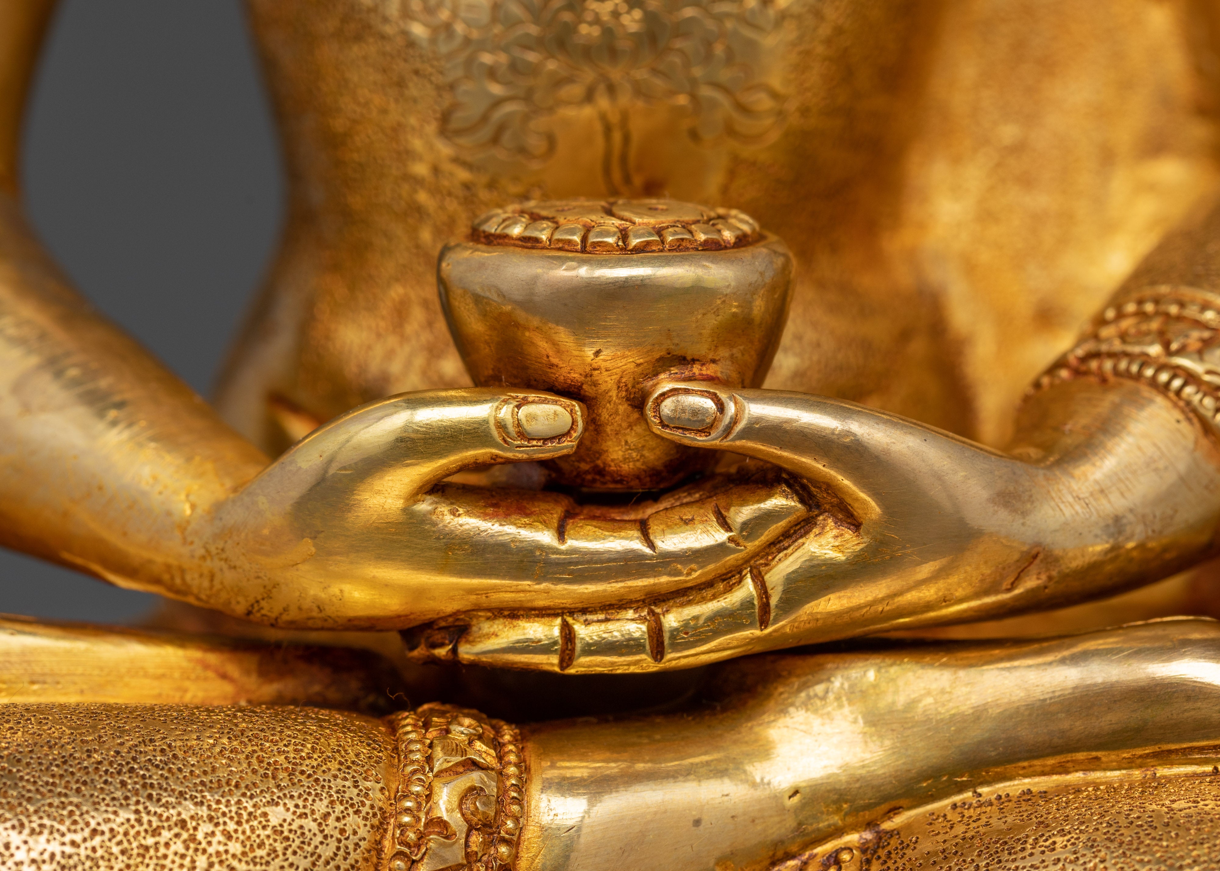 Close-up of Amitabha Buddha fire-gilded sculpture holding monk’s bowl, Himalayan icon