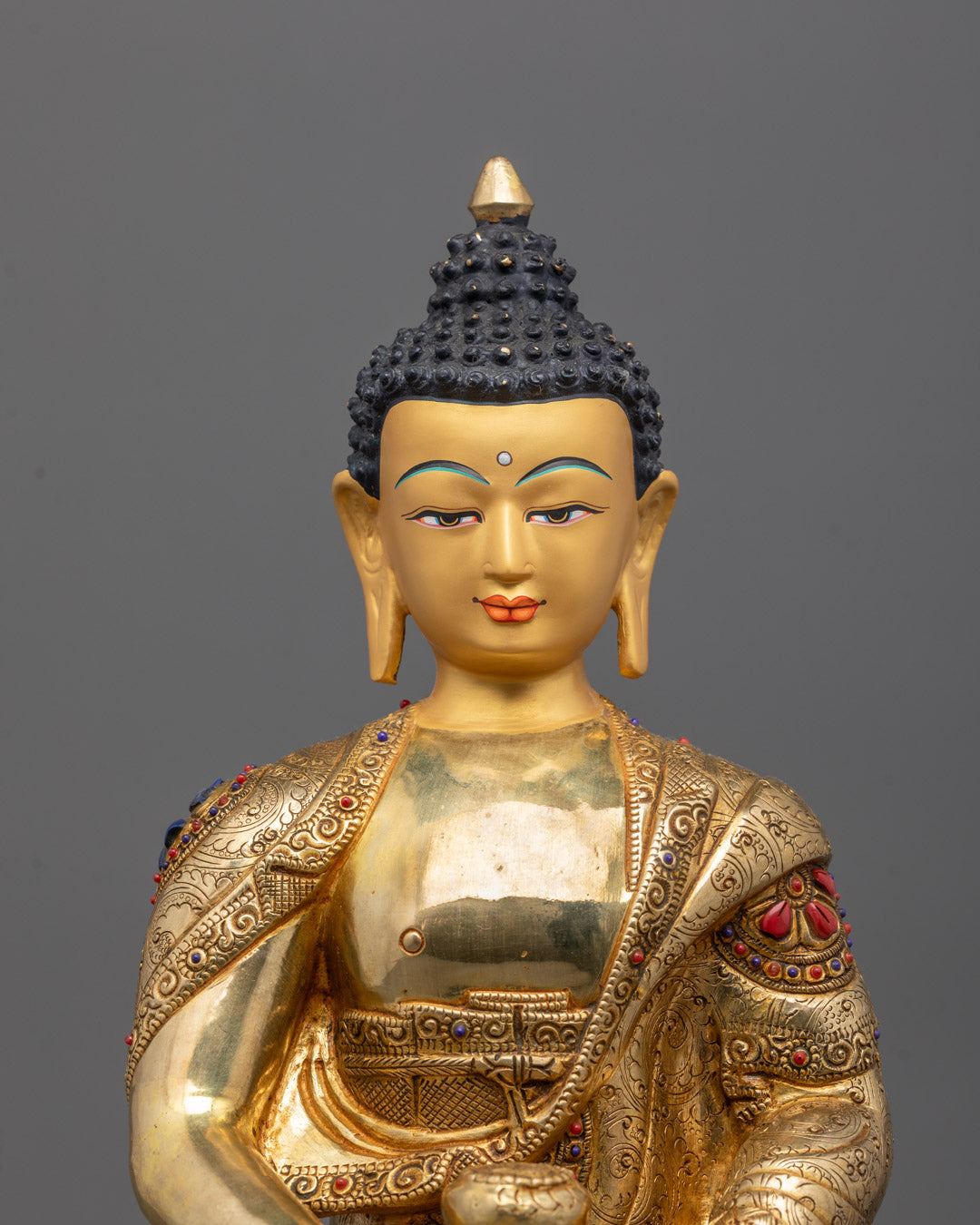 Close-up of Amitabha Buddha’s serene 24k gilded gold face adorned with semi-precious stones