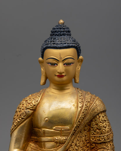 Amitabha Buddha’s serene face on a copper statue adorned with vibrant acrylic colors and gold leaf detailing.