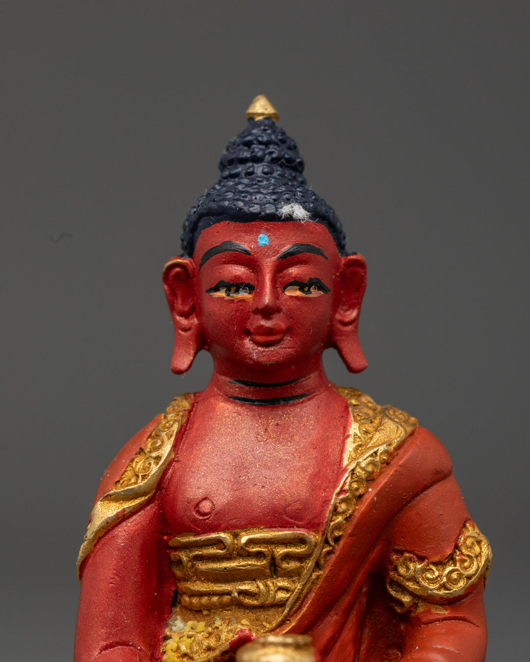 Close-up of Amitabha Buddha’s serene face with intricate details and vibrant red color
