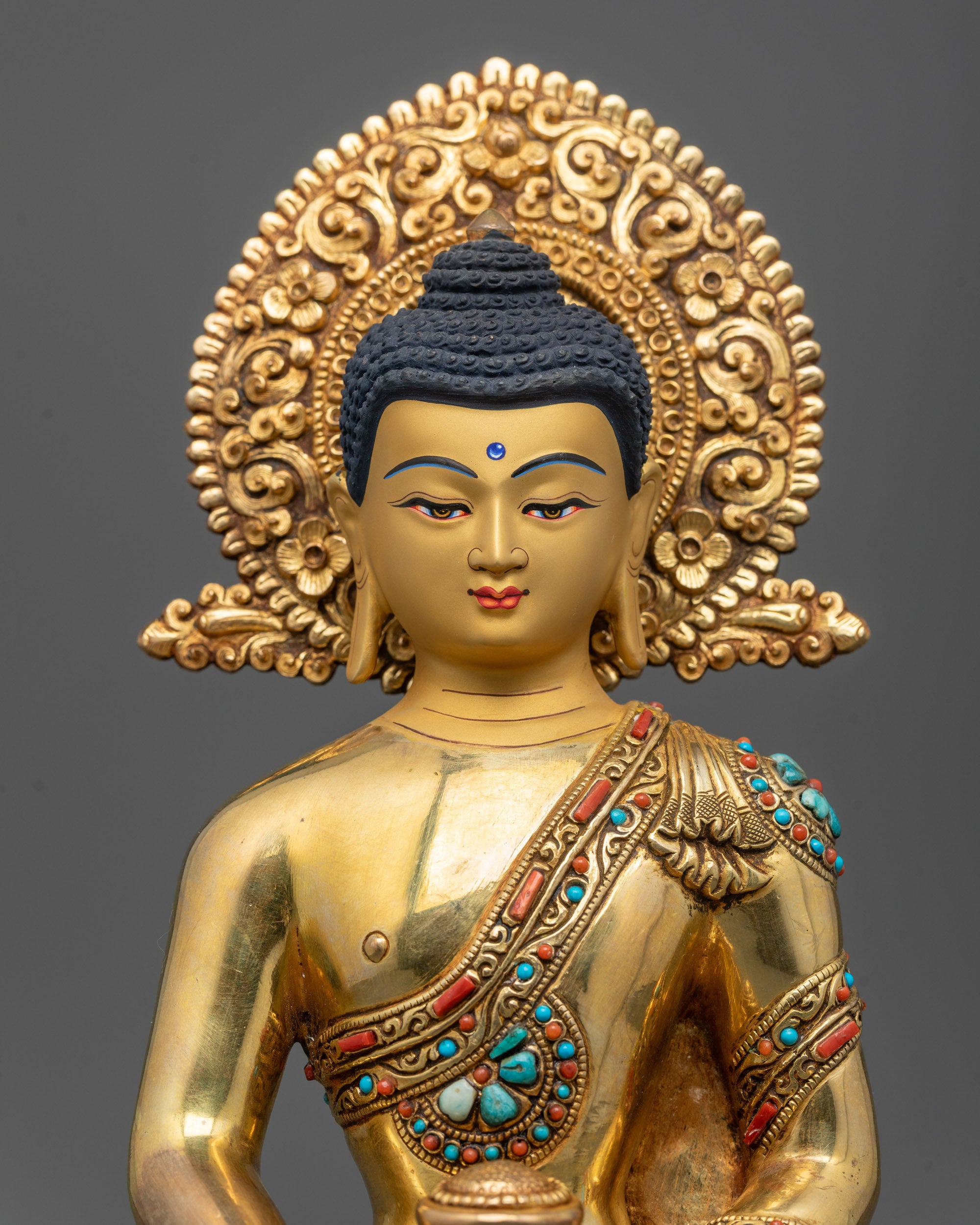 Close-up of Amitabha Buddha's serene gold-gilded face adorned with semi-precious stones