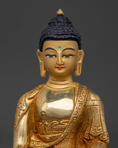 Close-up of Buddha Sakyamuni statue showing detailed monastic robes and fire-gilded face