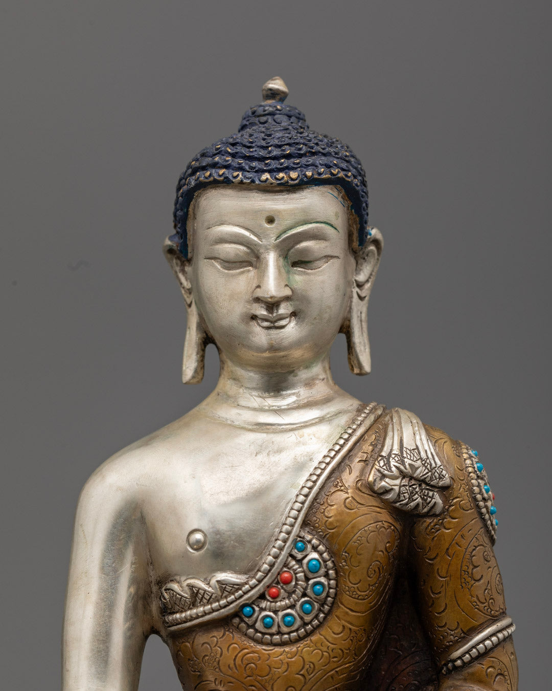 Buddha Shakyamuni’s face and upper body, highlighting silver finish and detailed craftsmanship.