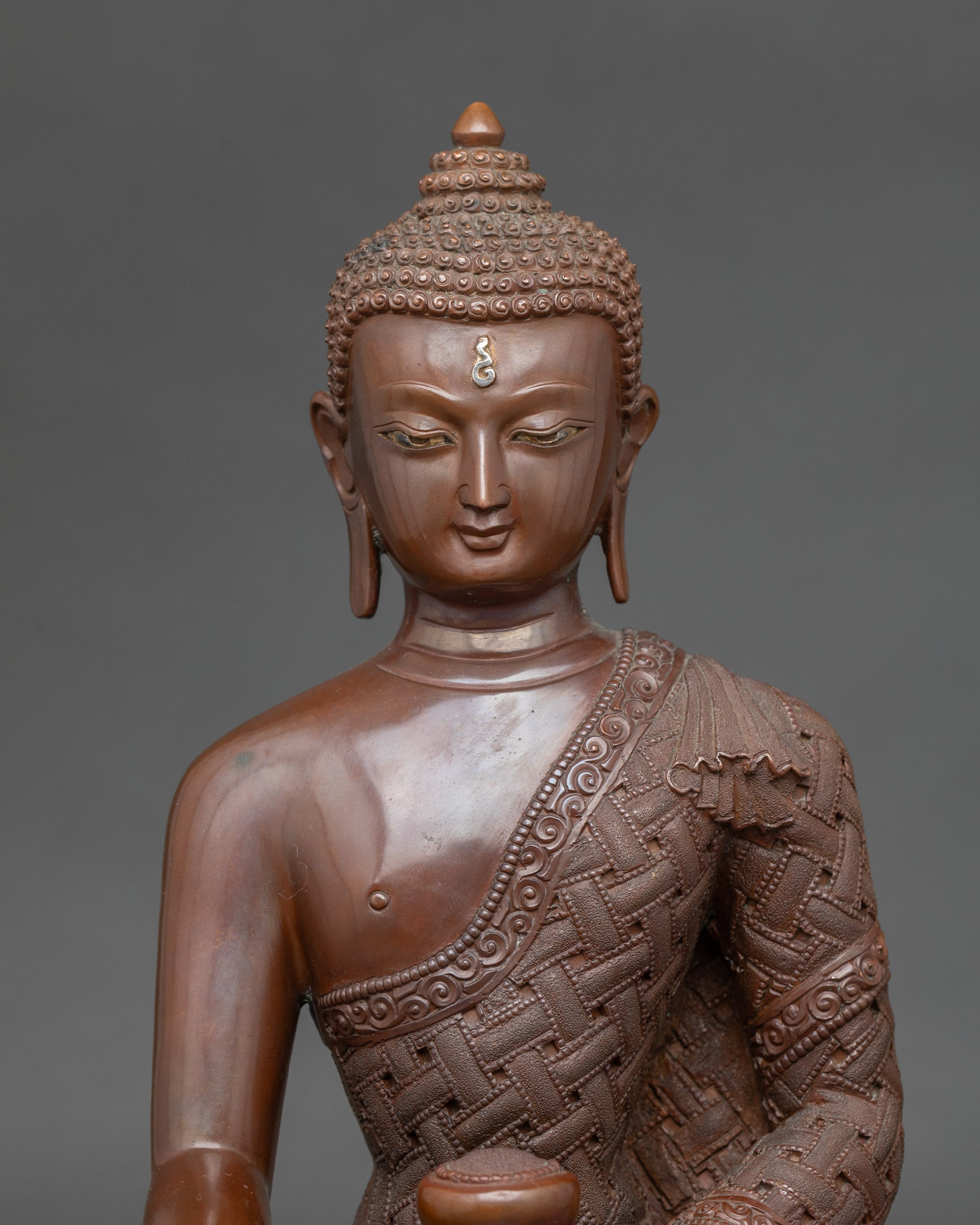Close-up of Buddha Shakyamuni statue showing serene face and monk’s bowl details