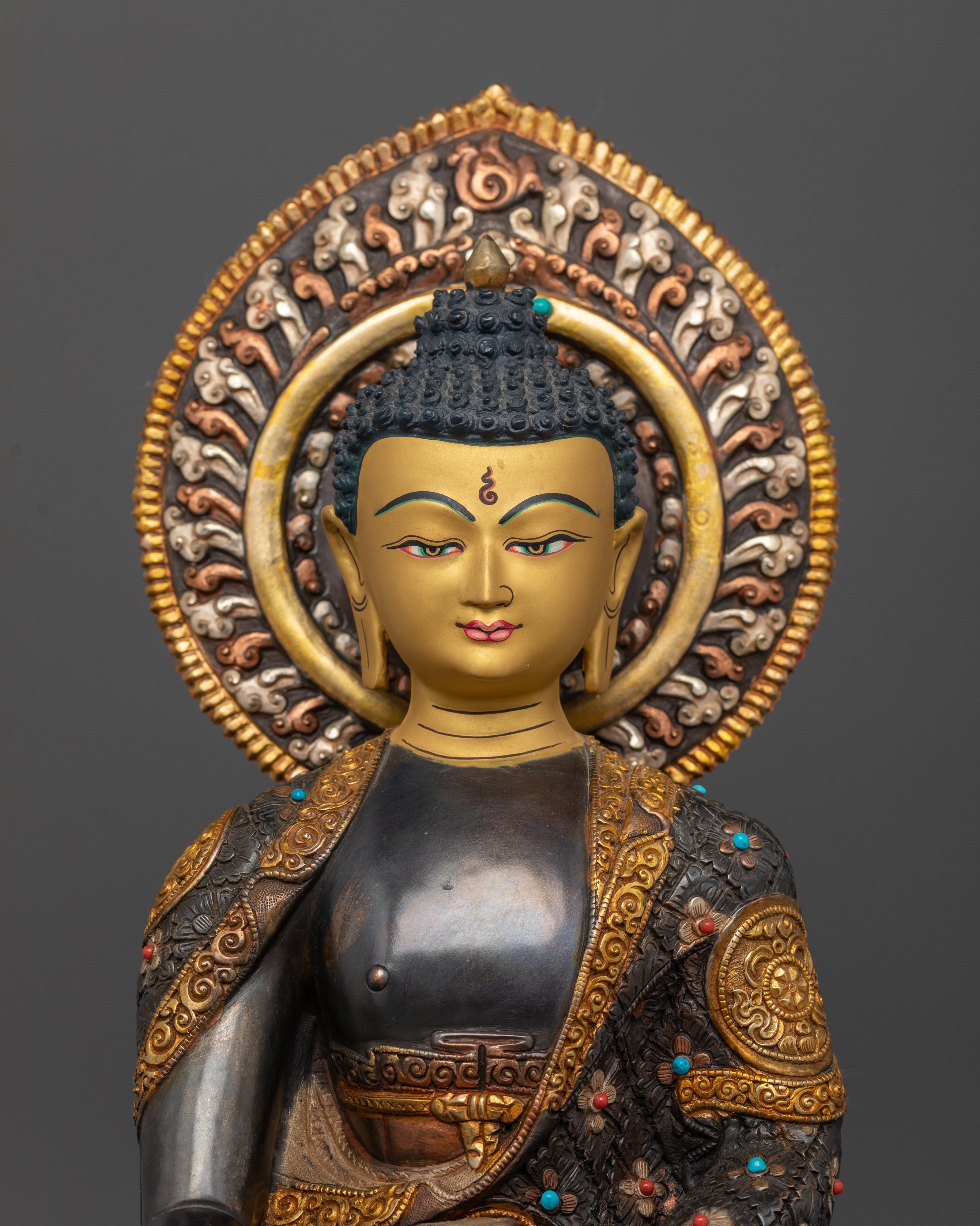 Close-up of Buddha idol face showing intricate gold-plated details and semi-precious stones