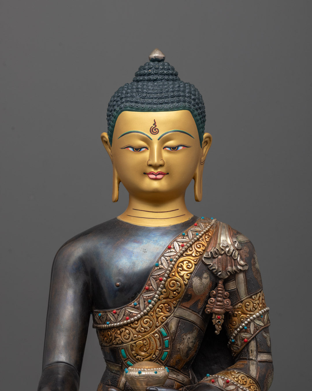 Close-up of Buddha’s jewel-adorned patra bowl, monk’s robe, and gold, silver, and copper plating