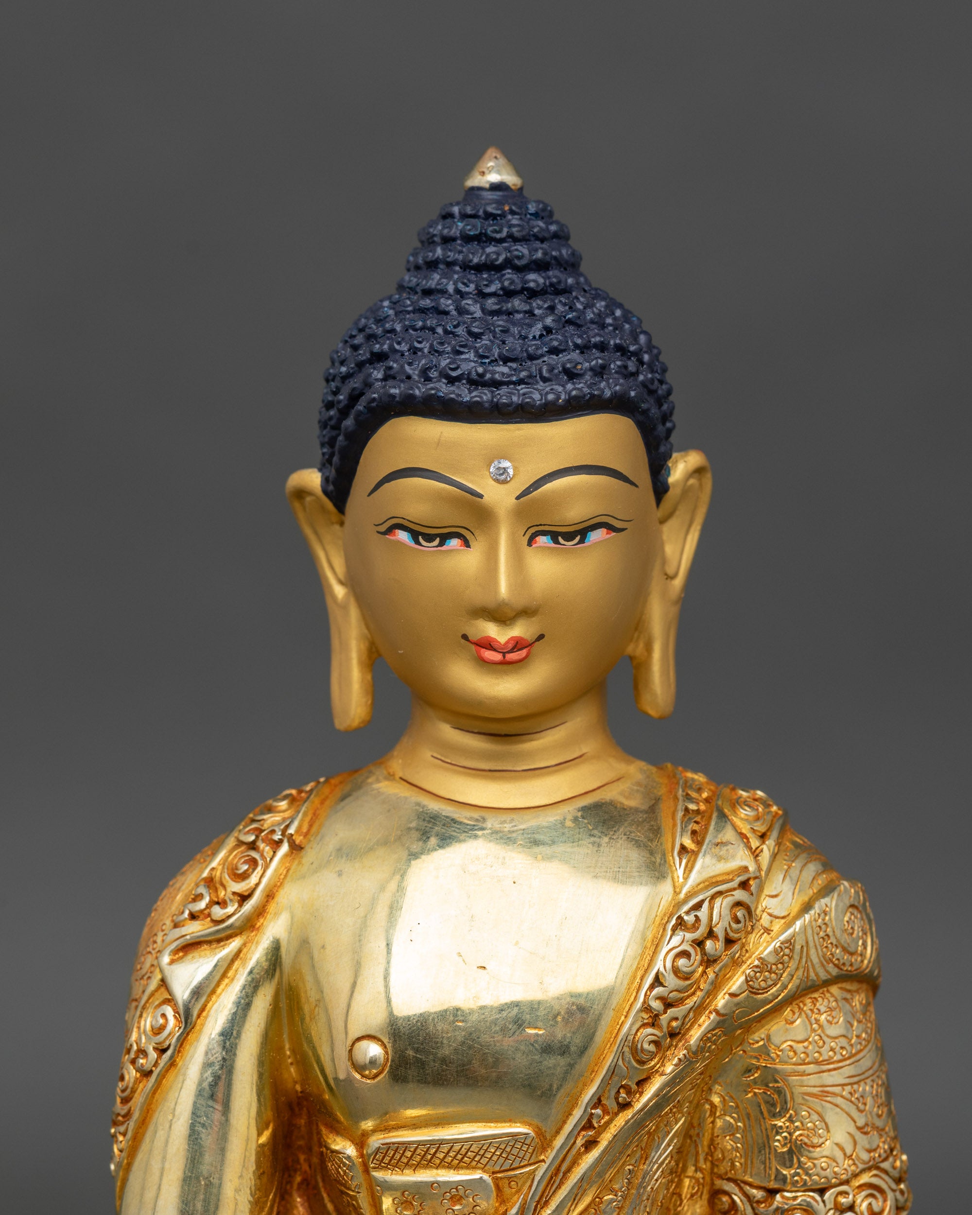 Close-up of Buddha statue face, gold-painted, embodying wisdom and compassion