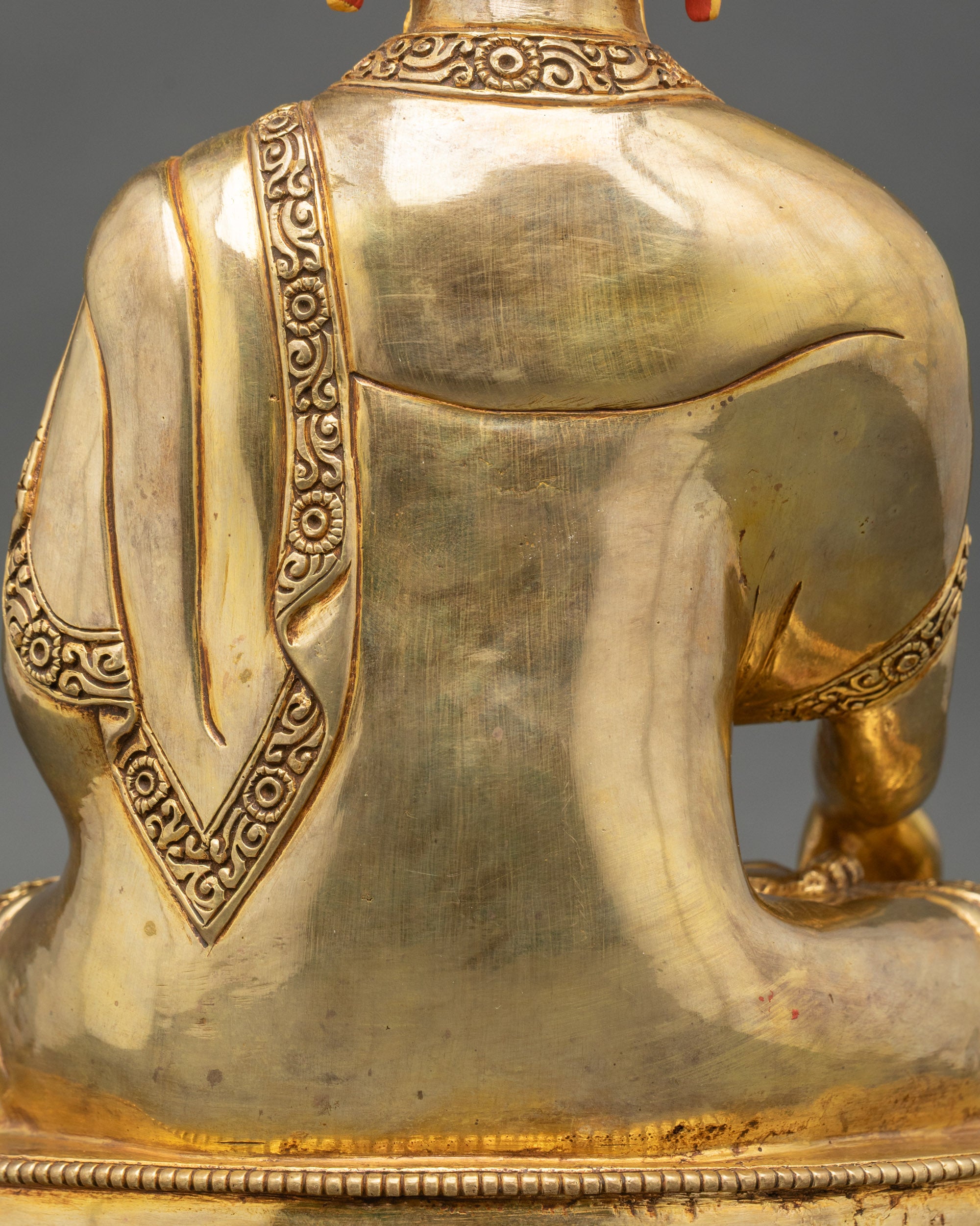 Close-up of Buddha statue showing intricate robe details and gold finish