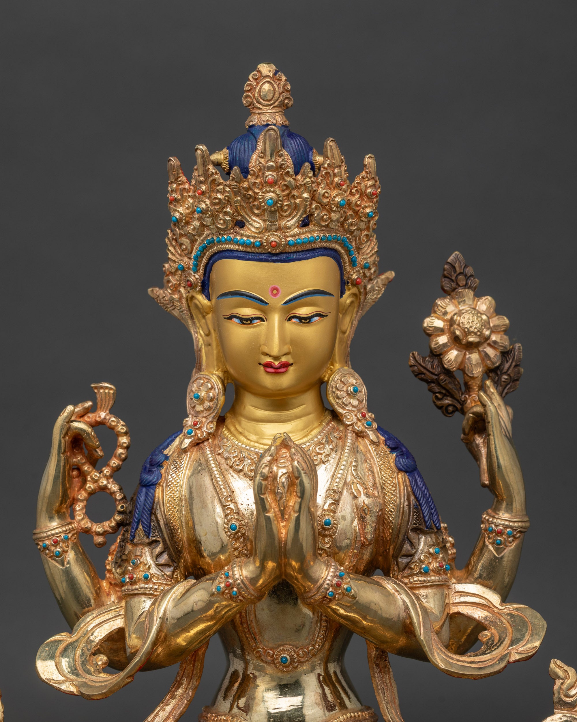 Close-up of Chenrezig Bodhisattva statue showing four arms with lotus, mala, and jewel