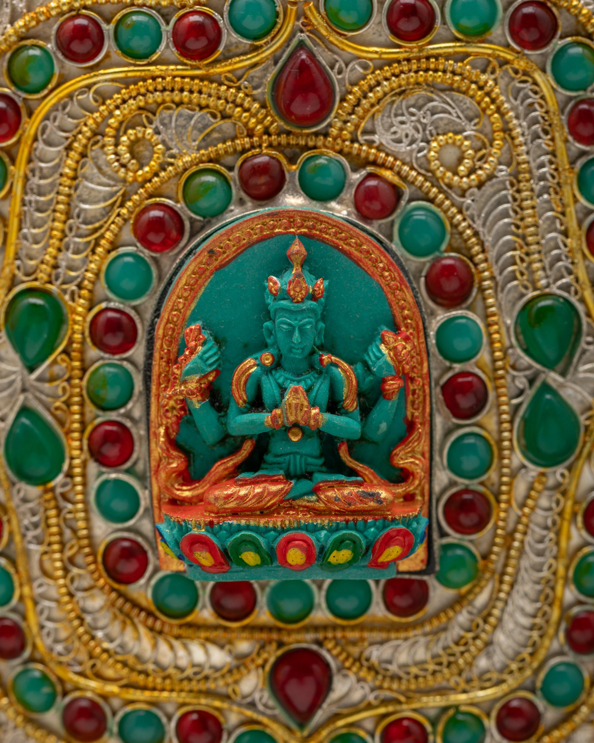 Close-up of Chenrezig carving on Himalayan Flower Vase representing compassion, hand-embellished with semi-precious turquoise and coral stones.