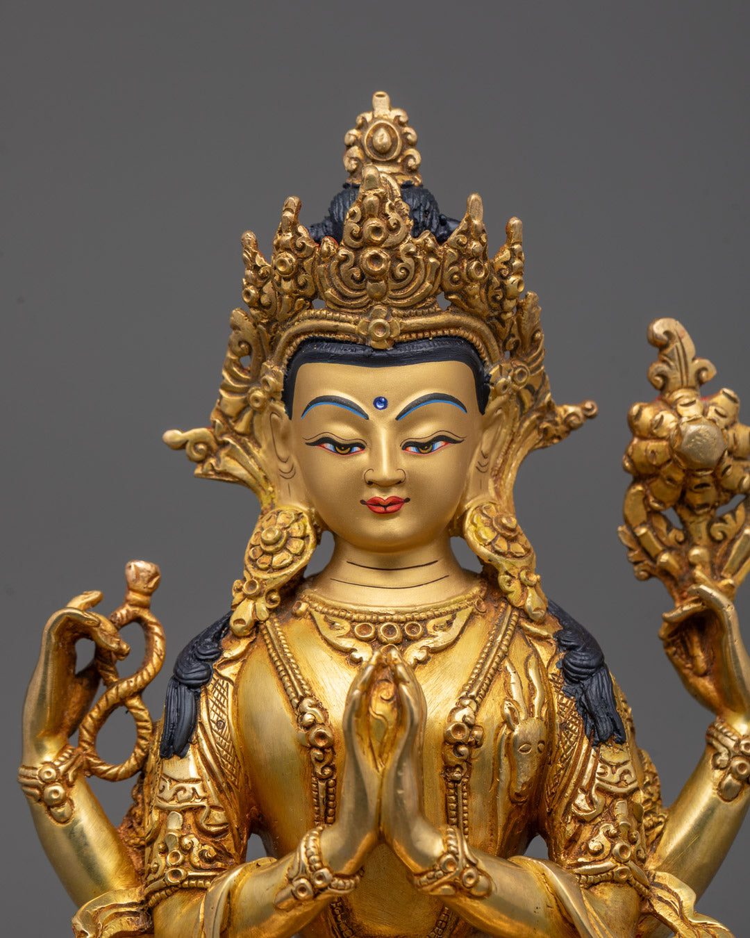 Close-up of Chenrezig’s serene face and four arms holding symbolic objects