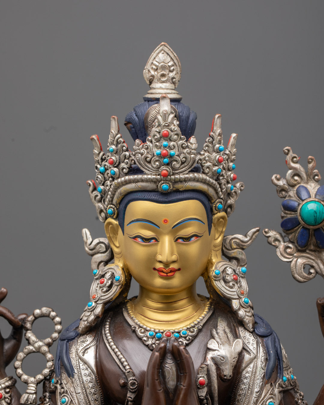 Chenrezig statue's serene 24k gold-gilded face, symbolizing compassion and divine wisdom in Tibetan Buddhist art
