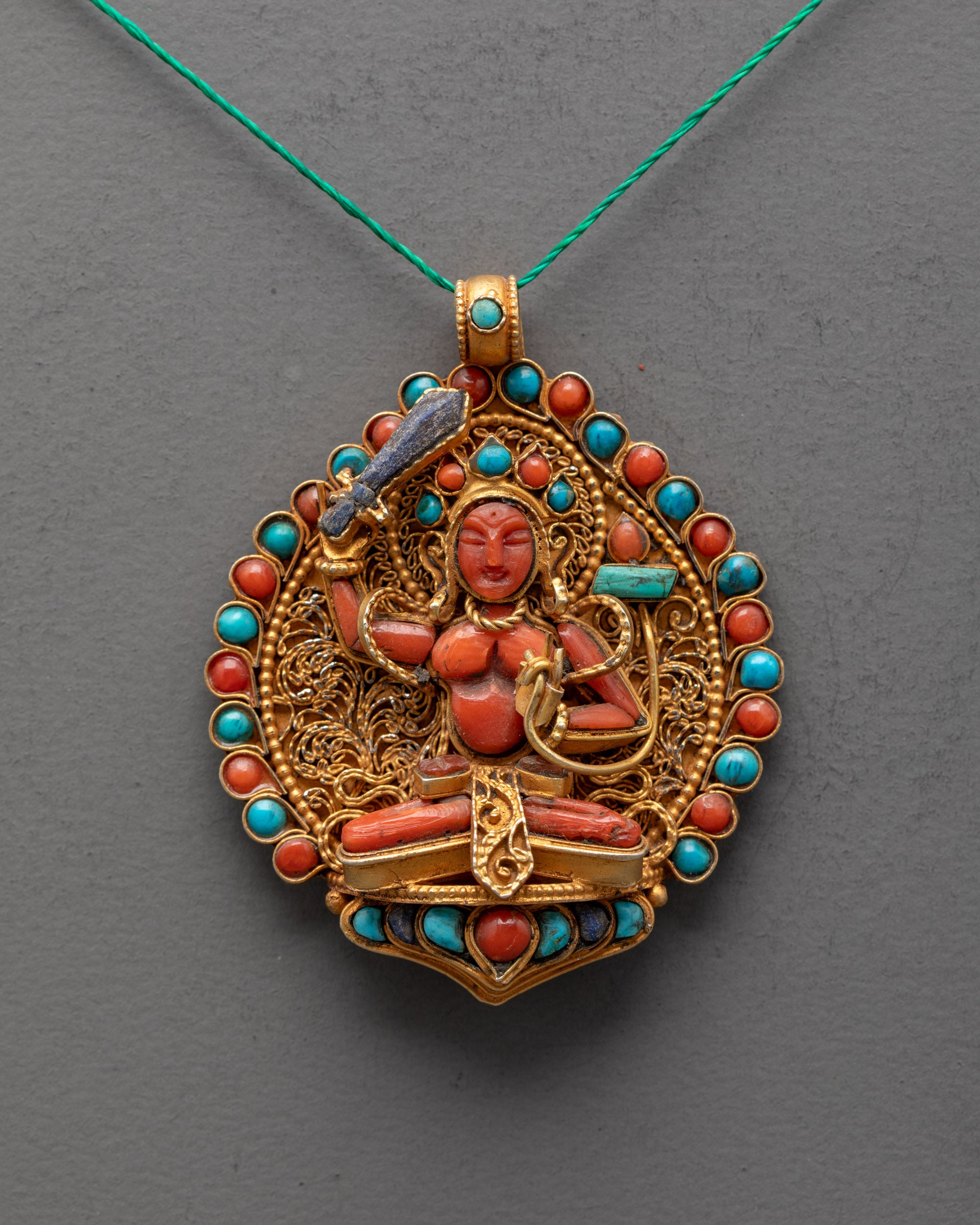 Close-up of Coral Manjushri pendant showing lapis sword, turquoise Prajna Paramita, fine detail