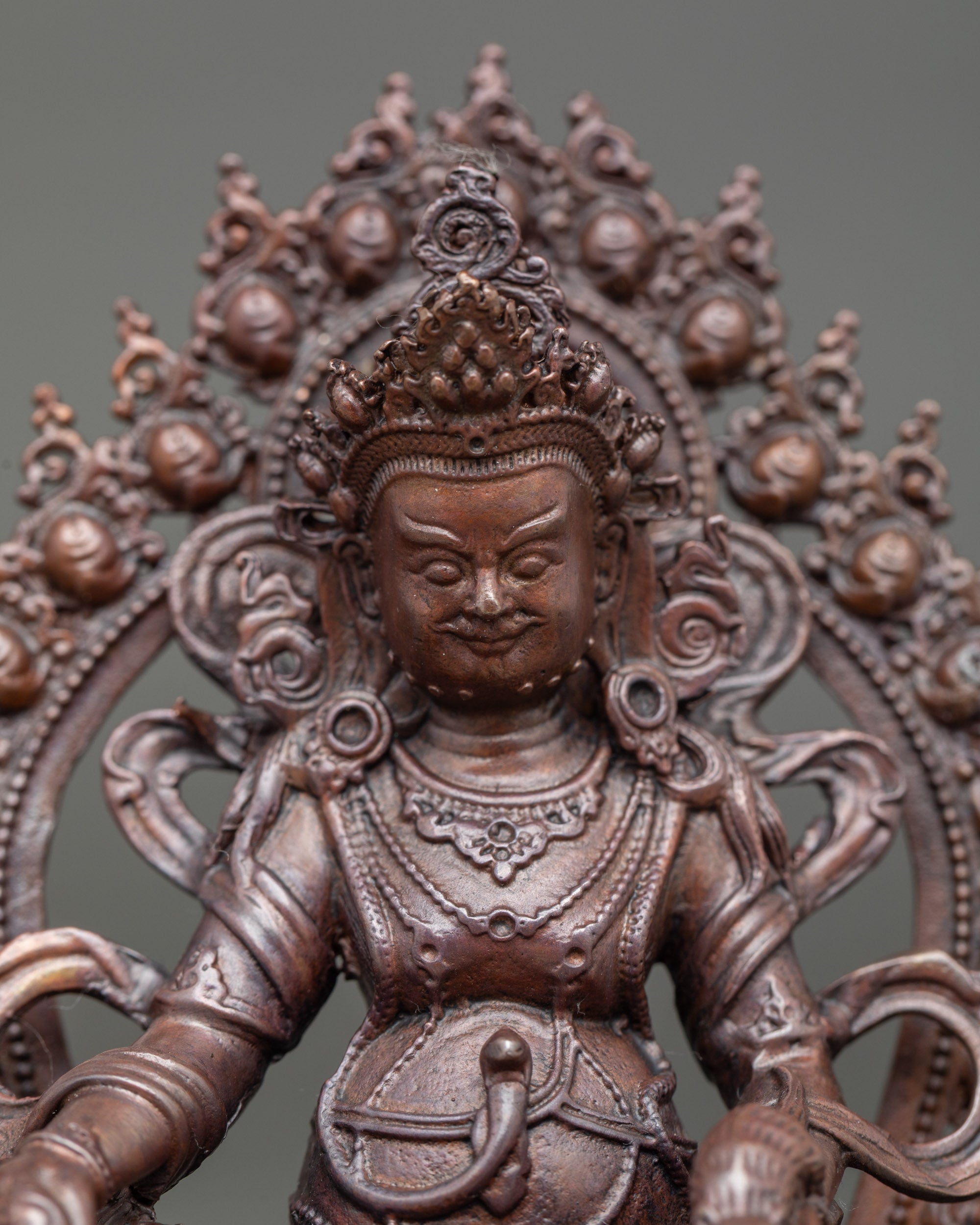 Close-up of Dzambhala face and right hand holding citron fruit, jewel, or jewel-spitting trident