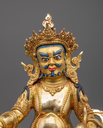 Close-up of Dzambhala's face and ornate crown, hand-carved with gold-plated copper