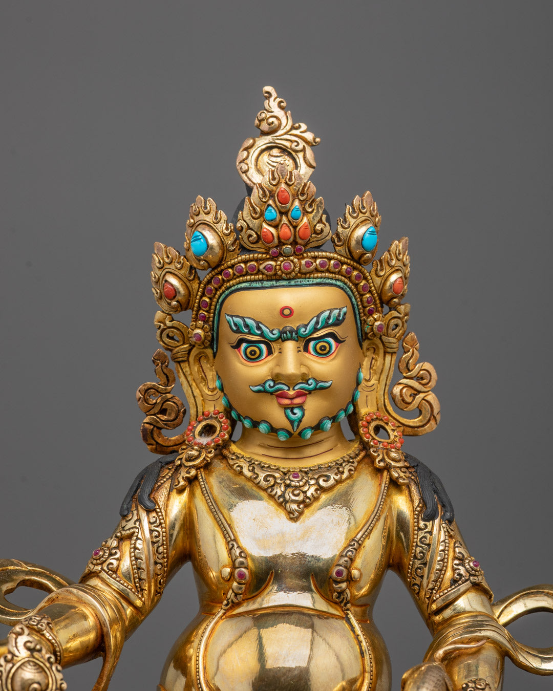 Close-up of Dzambhala’s serene face, ornate crown, and 24k gold gilded copper detailing