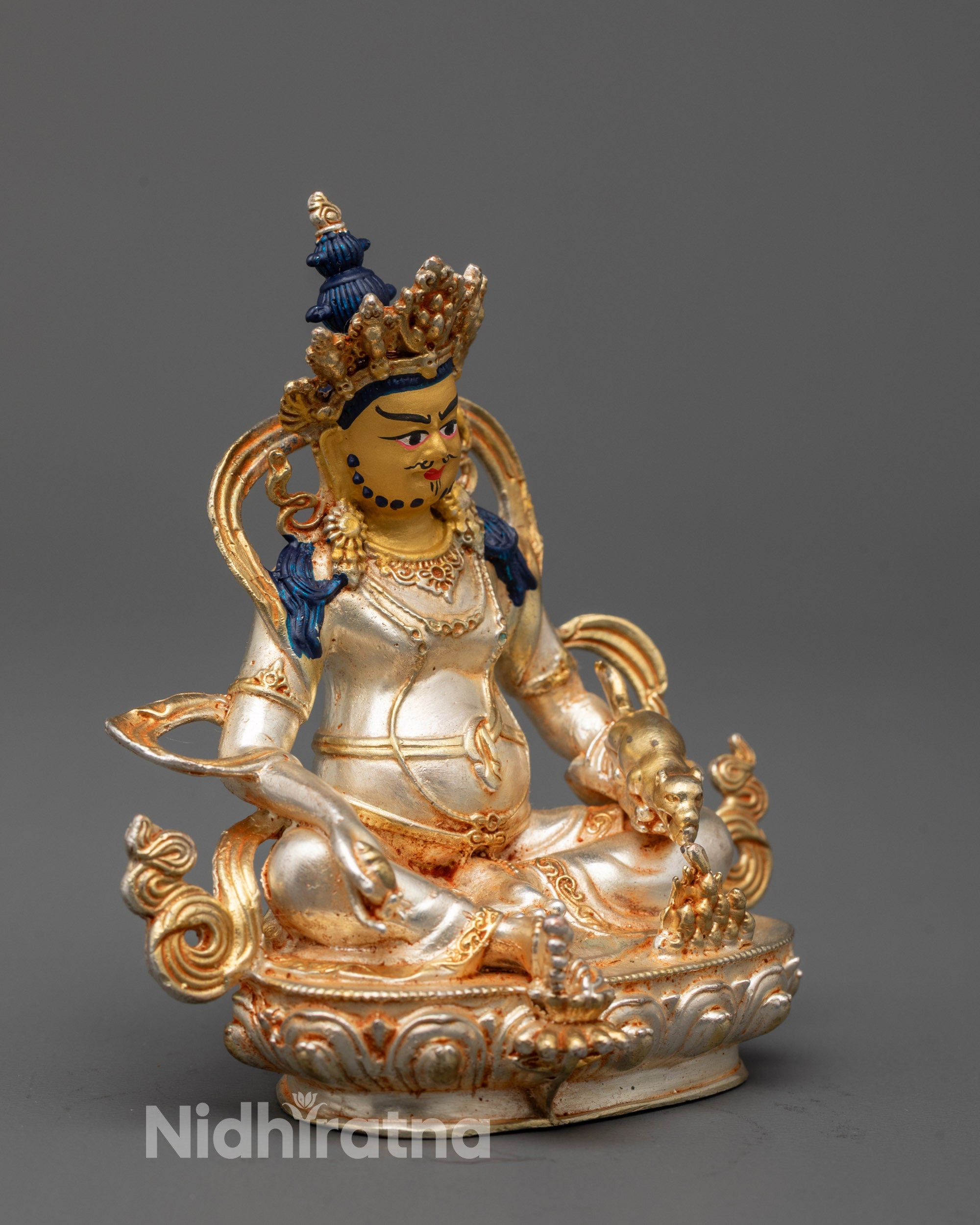 Close-up of Dzambhala statue’s five jeweled crown and flowing robe details
