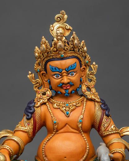 Close-up of Dzambhala statue showing vibrant robes and intricate lotus base