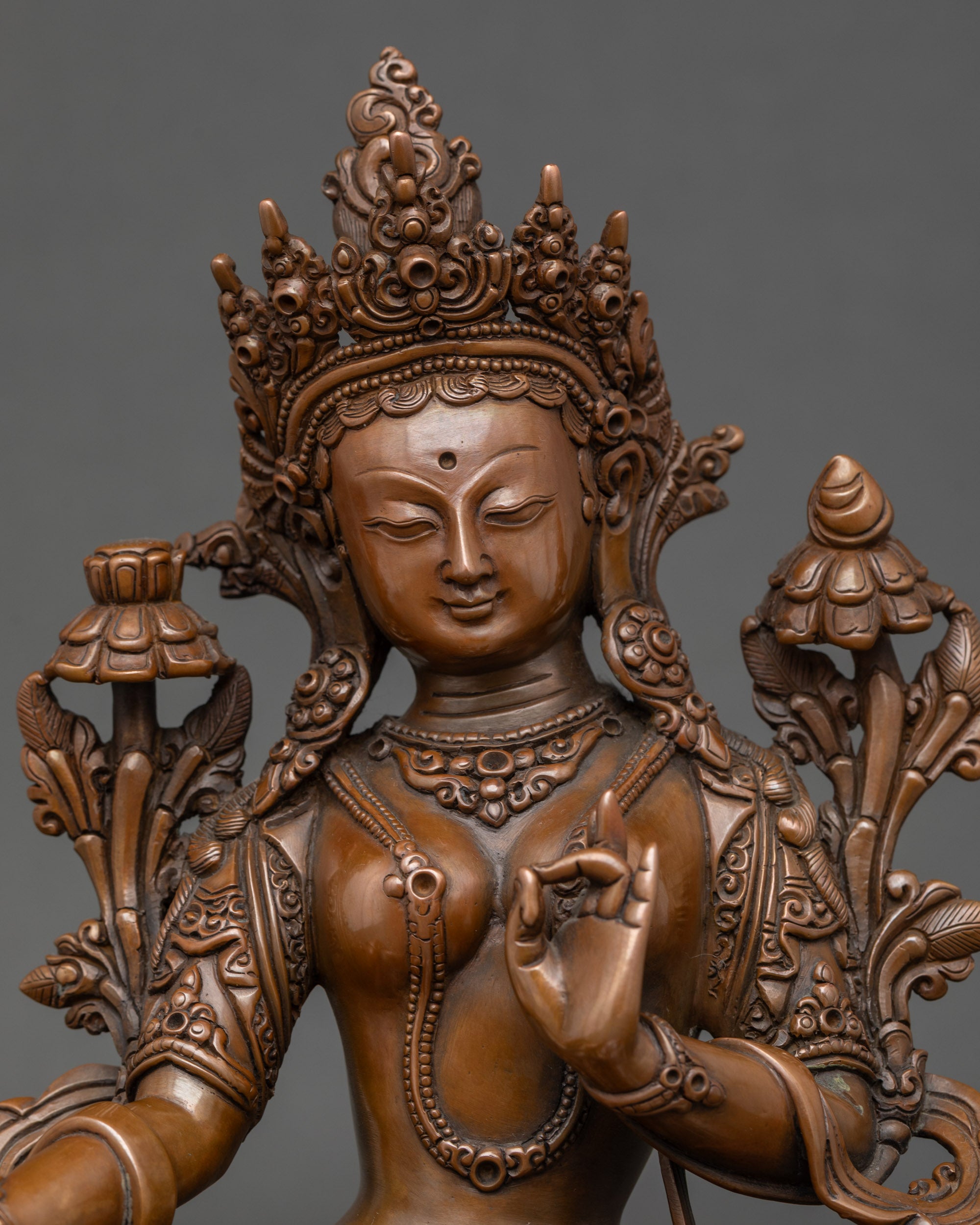 Close-up of Green Tara Bodhisattva face, hand-oxidized copper with utpala flowers