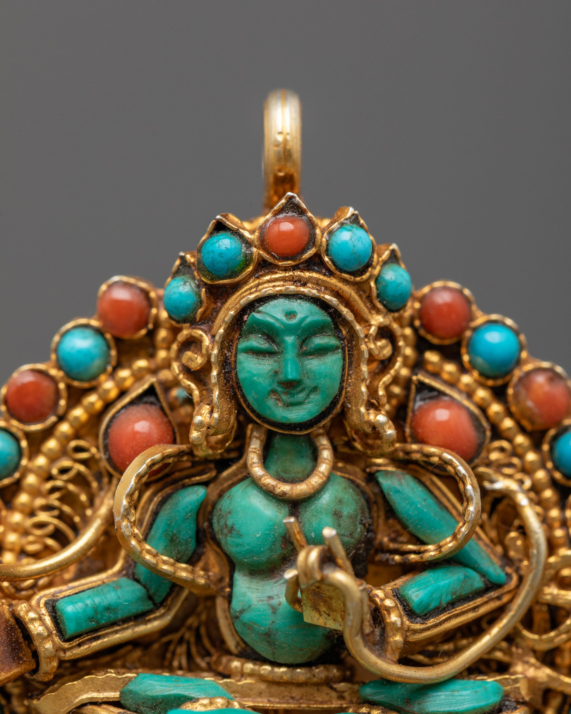 Close-up of Green Tara figure on gold-gilded locket with intricate filigree and stones